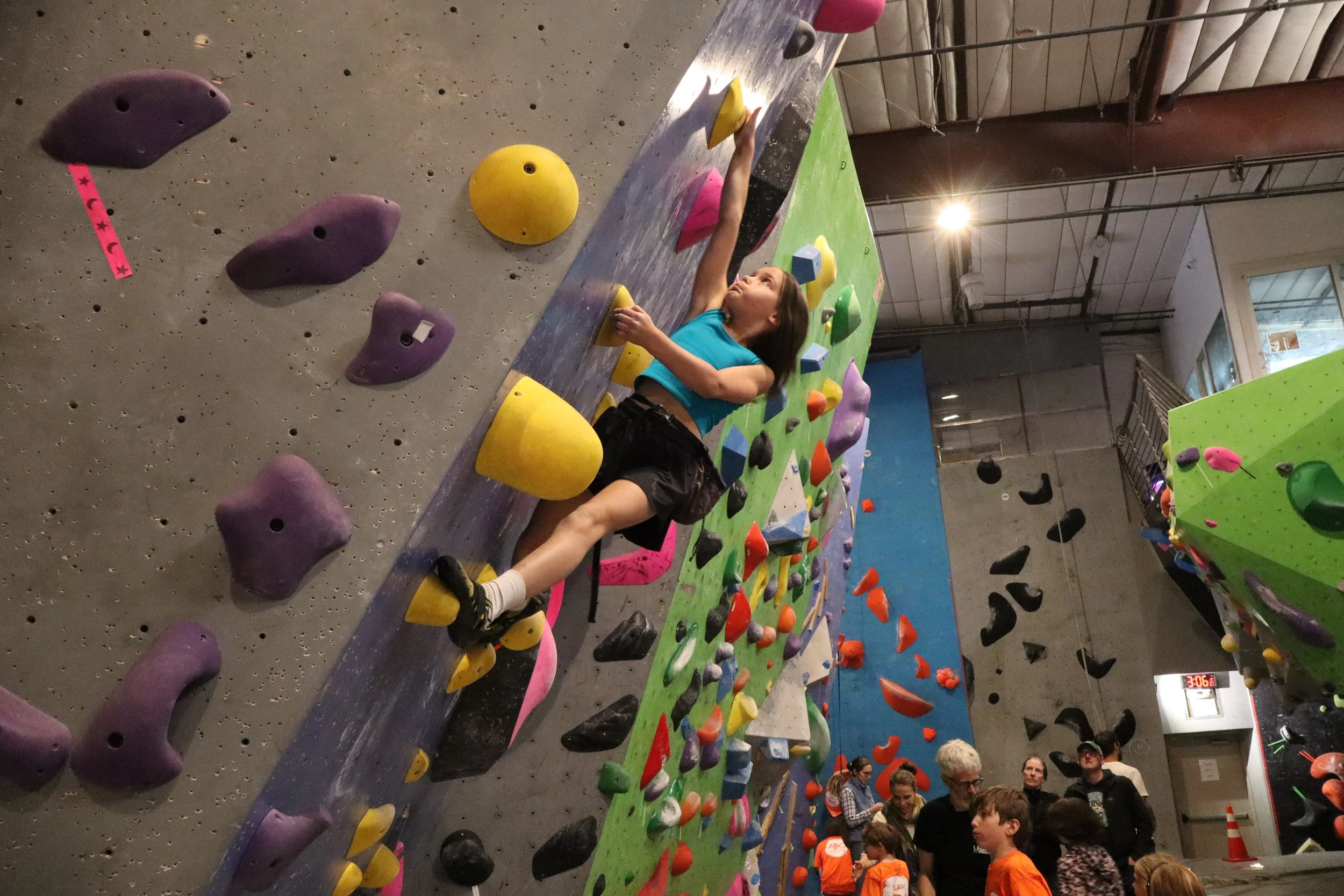 Super Stars Prep climber reaching for yellow holds on a steep green and gray wall at ABC Kids Climbing