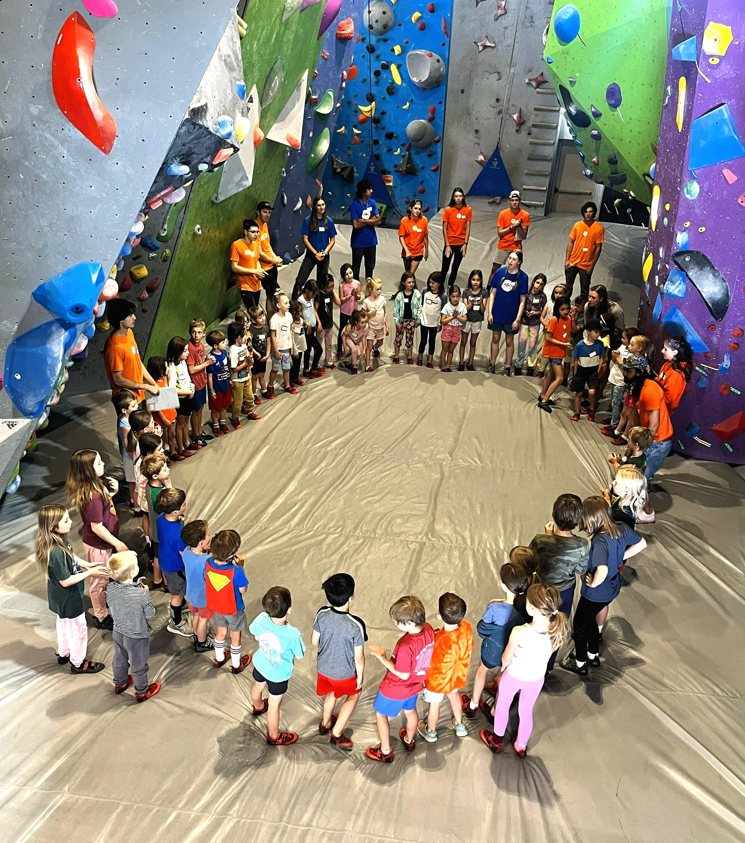 Large group of kids standing in a circle with ABC coaches during a group climbing visit at ABC Kids Climbing in Boulder