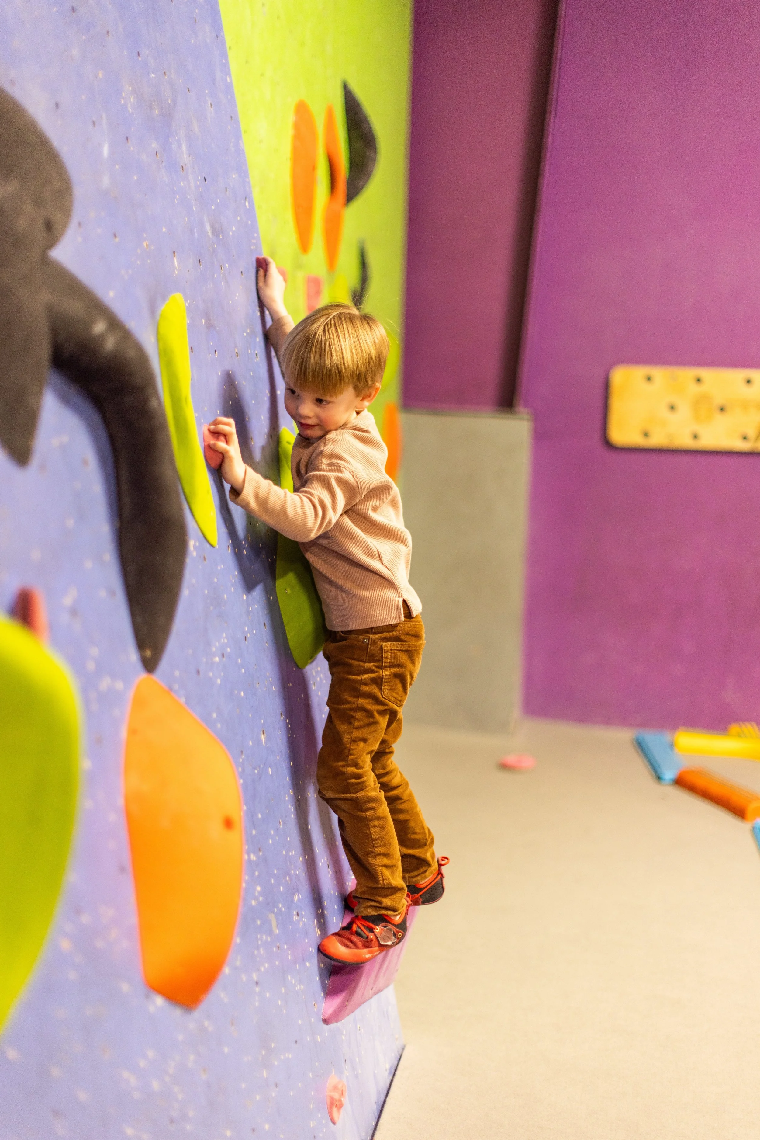 Preschool-age child climbing a colorful kids climbing wall at ABC Kids Climbing in Boulder
