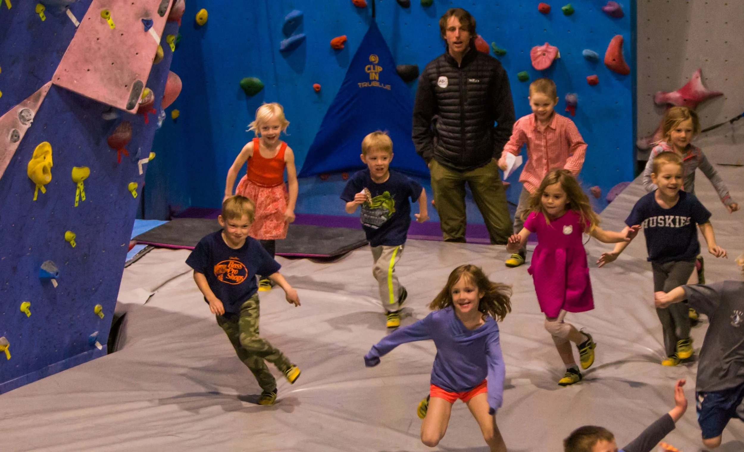Young kids running and playing games on the gym floor during a school day off climbing camp at ABC Kids Climbing in Boulder