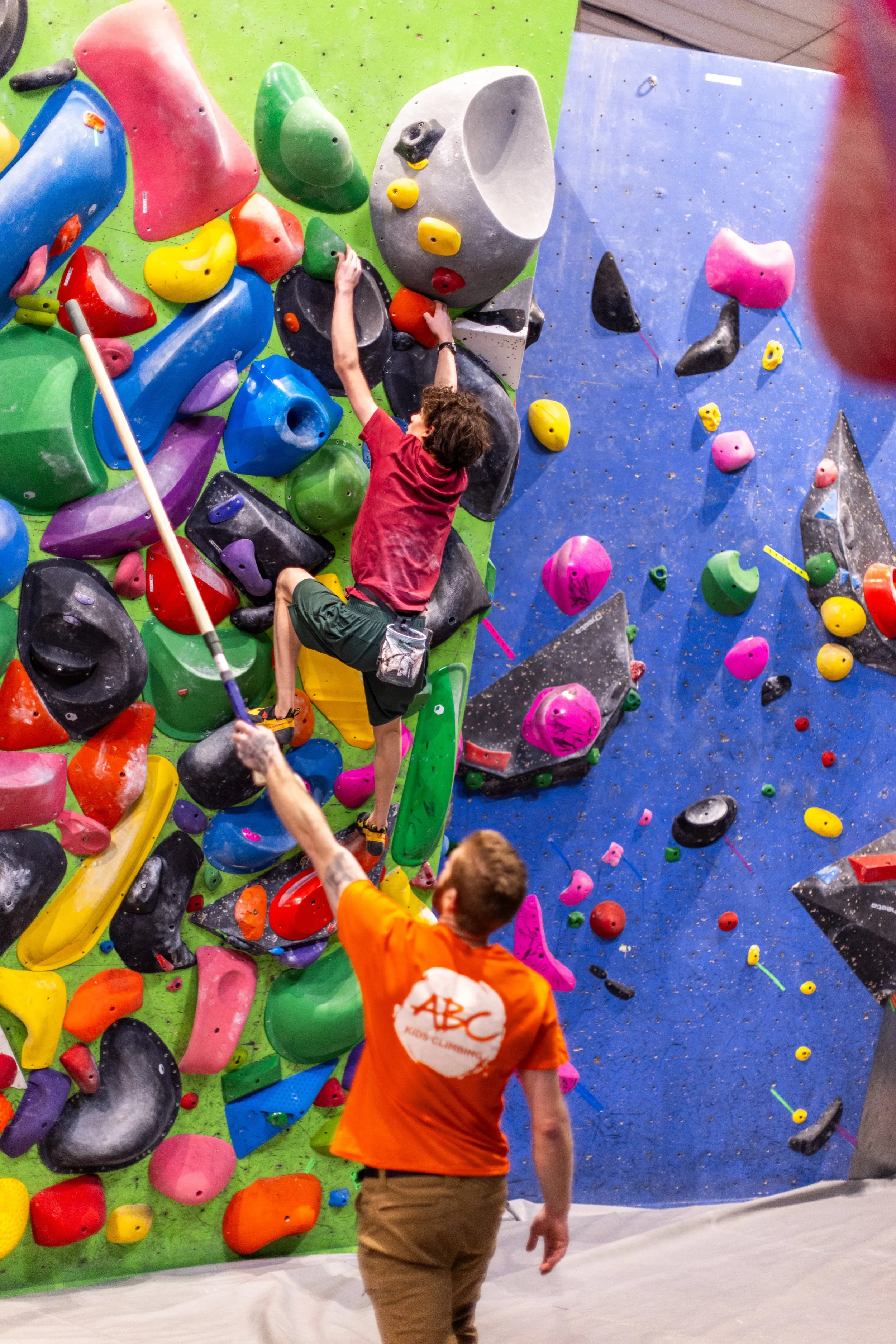 ABC coach belaying a young climber on a colorful wall during a private climbing lesson in Boulder