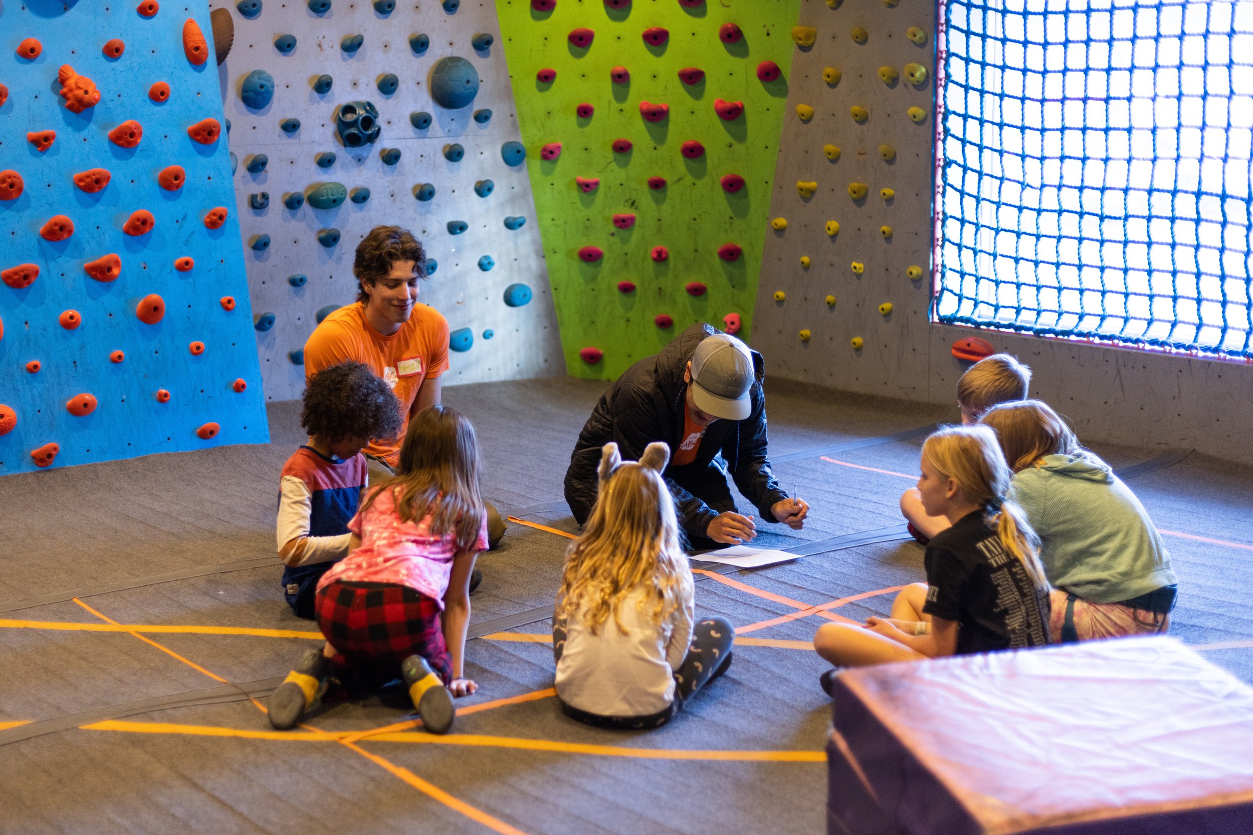 Young children sitting in a circle with climbing coaches during an ABC Kids climbing class in Boulder