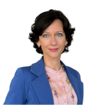 A woman with short dark hair, Sasha Mrak Hendrickson, wearing a blue blazer over a light pink shirt, smiling at the camera.