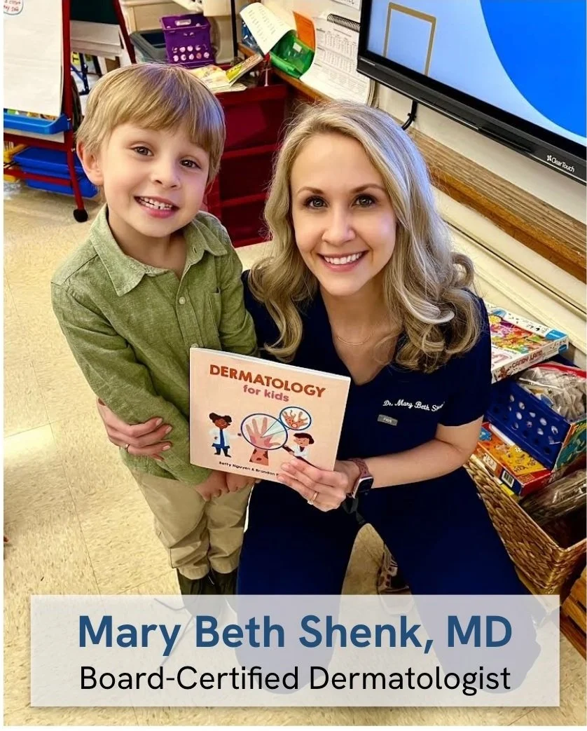 A woman with blonde hair, smiling, holding a children's book titled 'Dermatology for Kids' next to a boy with light brown hair, also smiling, in a classroom. The woman is wearing a navy blue uniform with a name tag, and the boy is dressed in a green button-up shirt and beige pants. They are posing next to a desk with educational materials and a television screen.