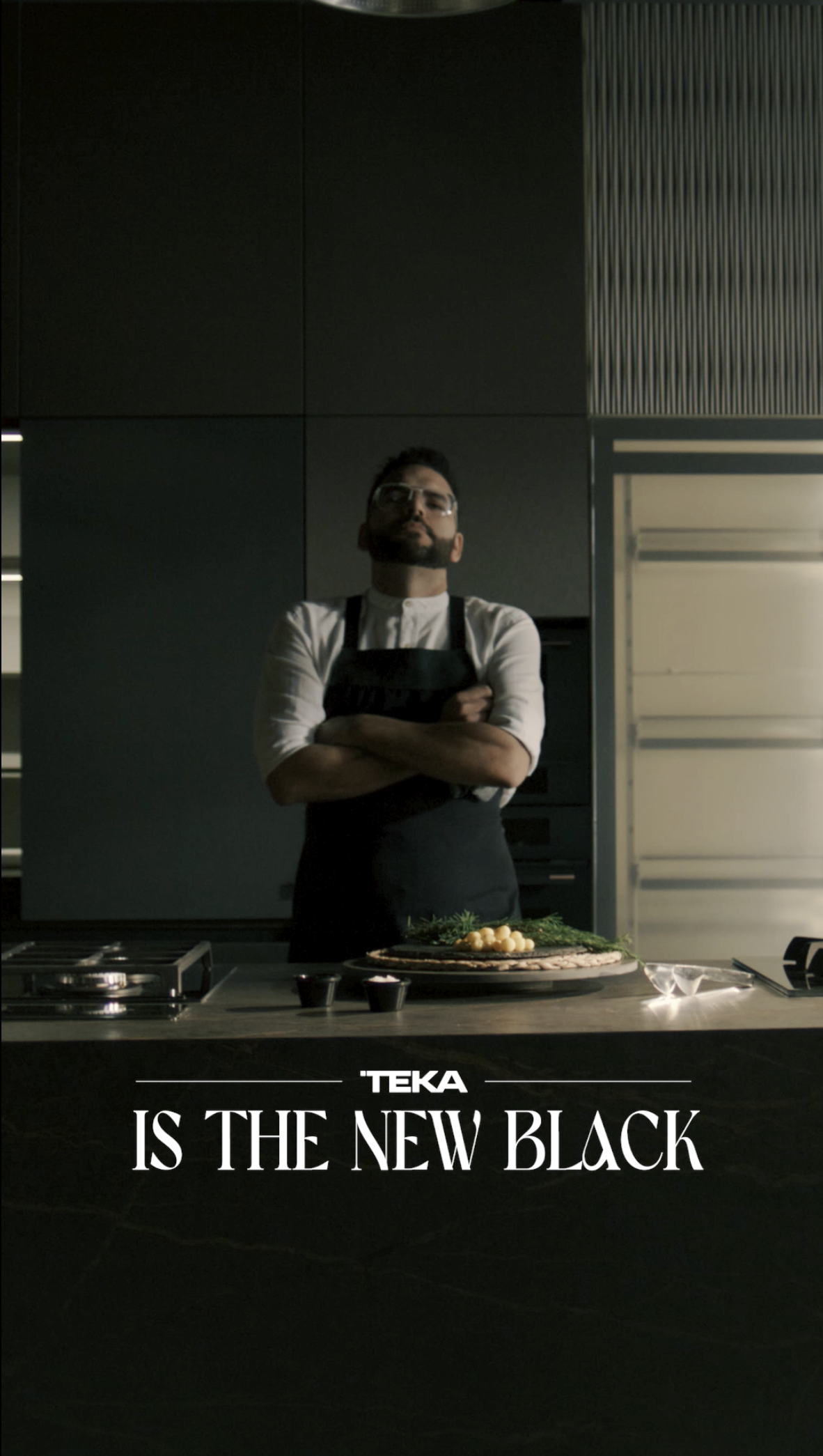 Un hombre parado en una cocina con tonalidades oscuras