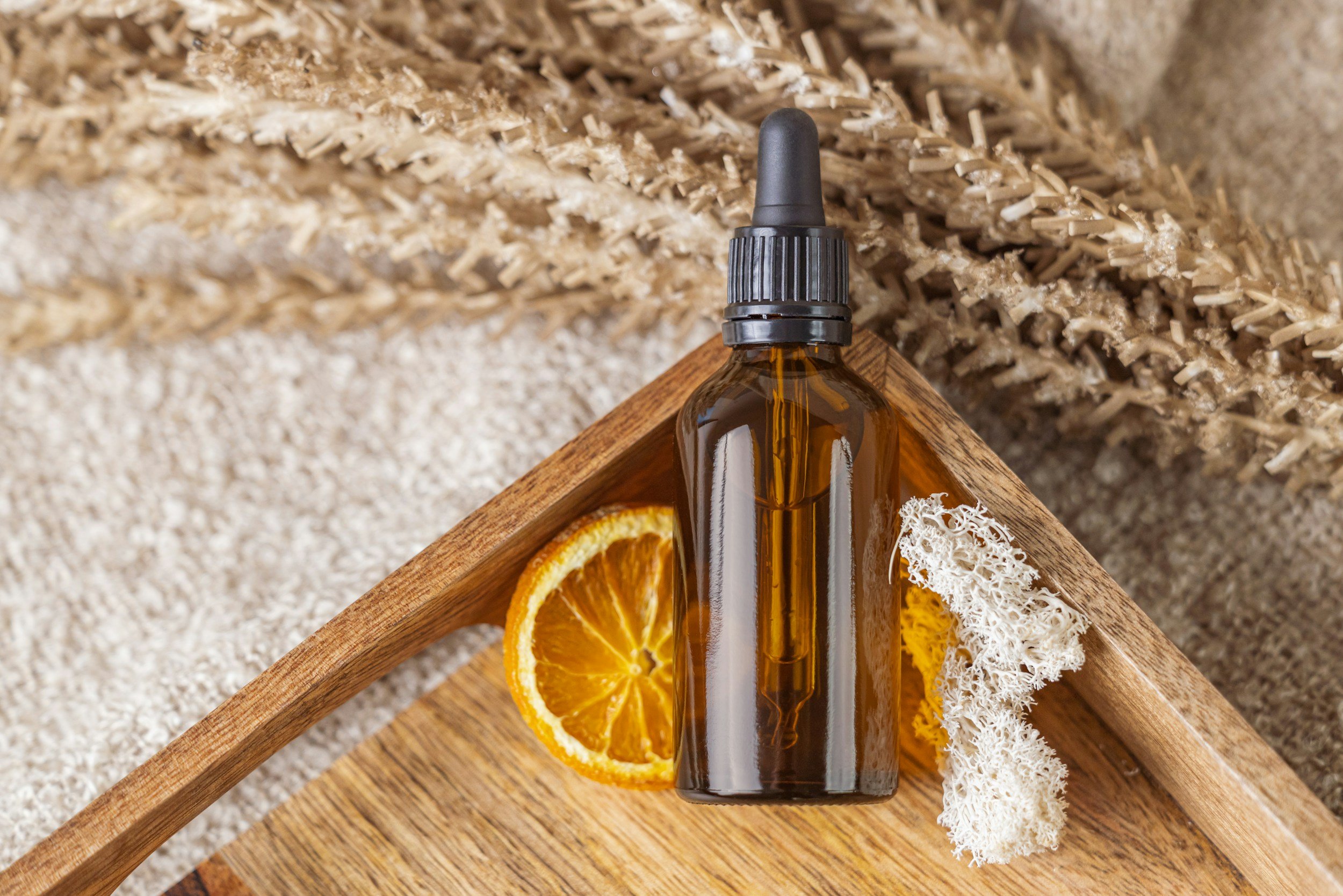 Dried orange slice and empty glass jar laying on a tray on a textured surface.