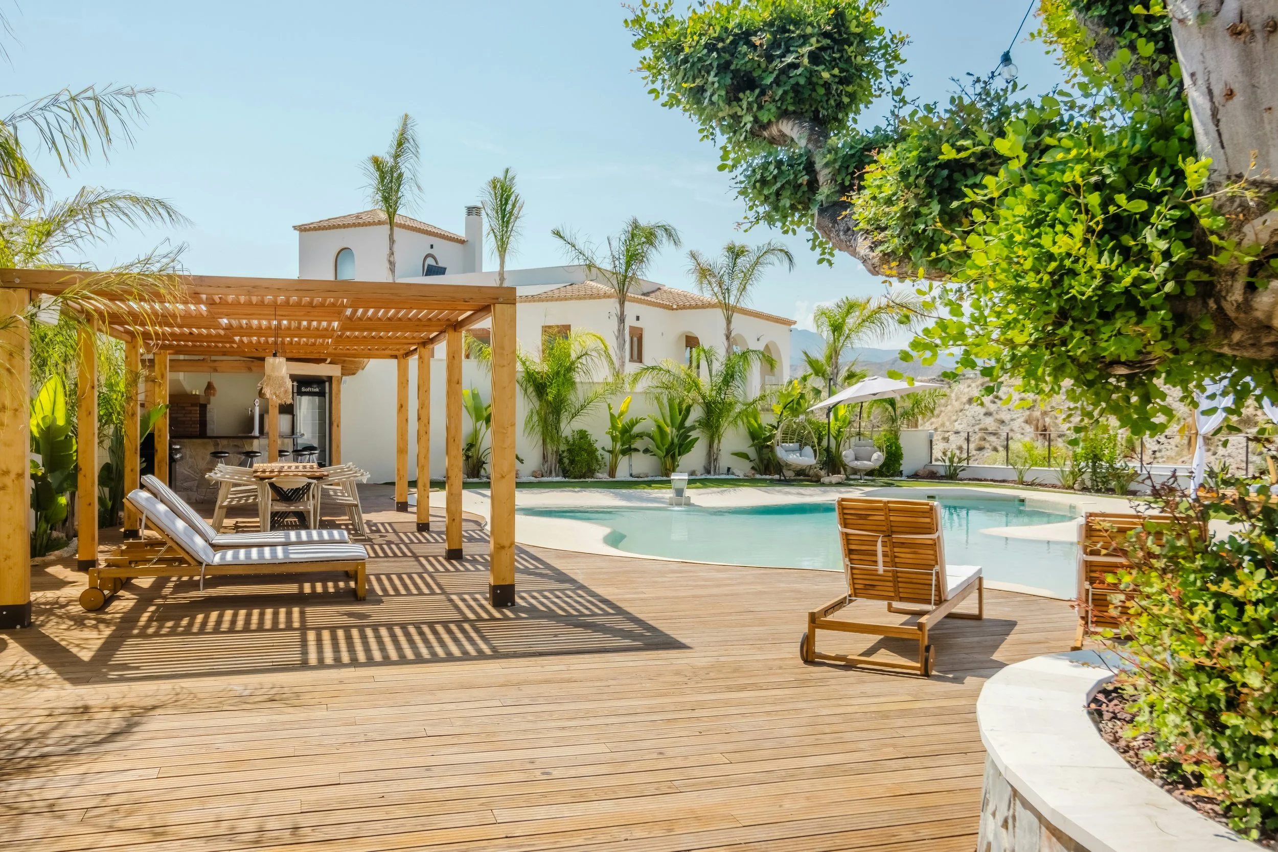 view of teak deck with loungers surrounding a pool and lush palm trees