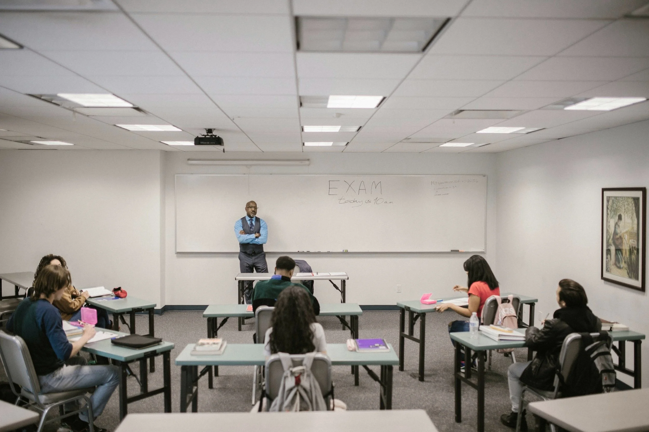 Classroom with several students and teacher standing at board