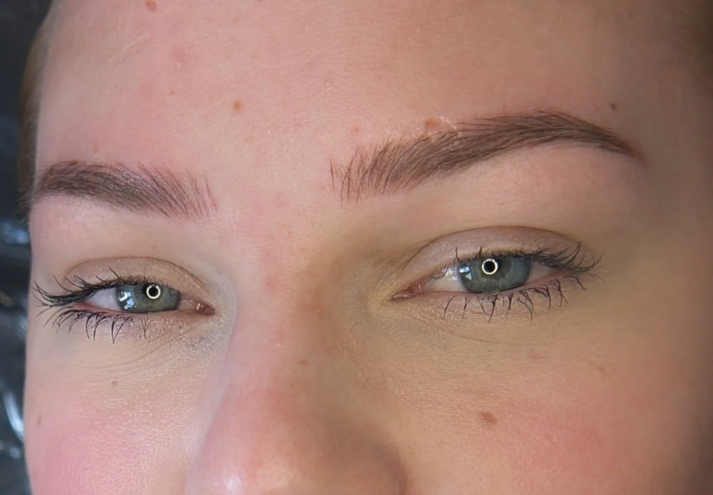 Close-up of a person's face focusing on the eyes and eyebrows, with visible skin and natural makeup.
