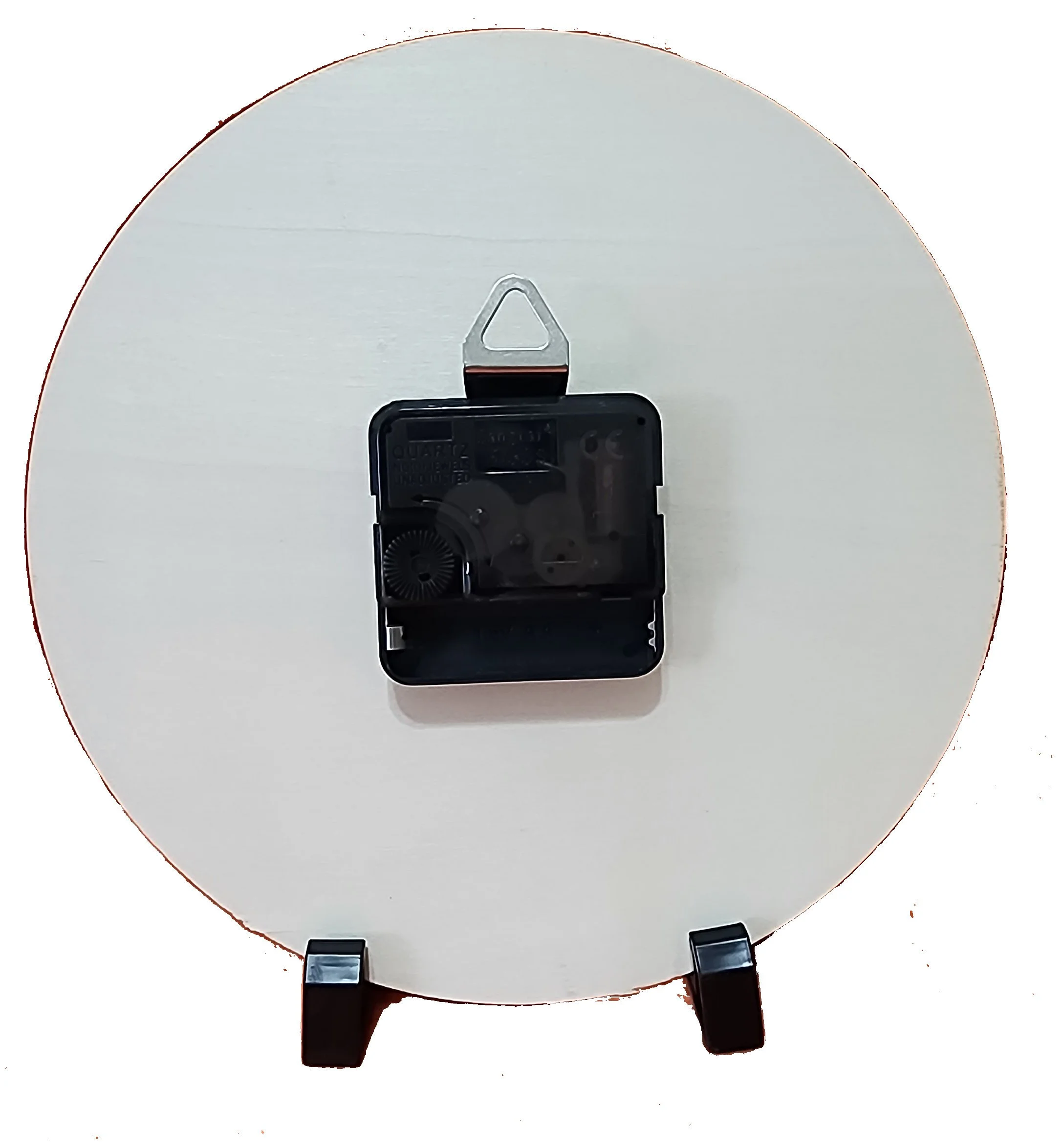 The back of a round white clock with black legs and a black clock movement mechanism attached in the center.