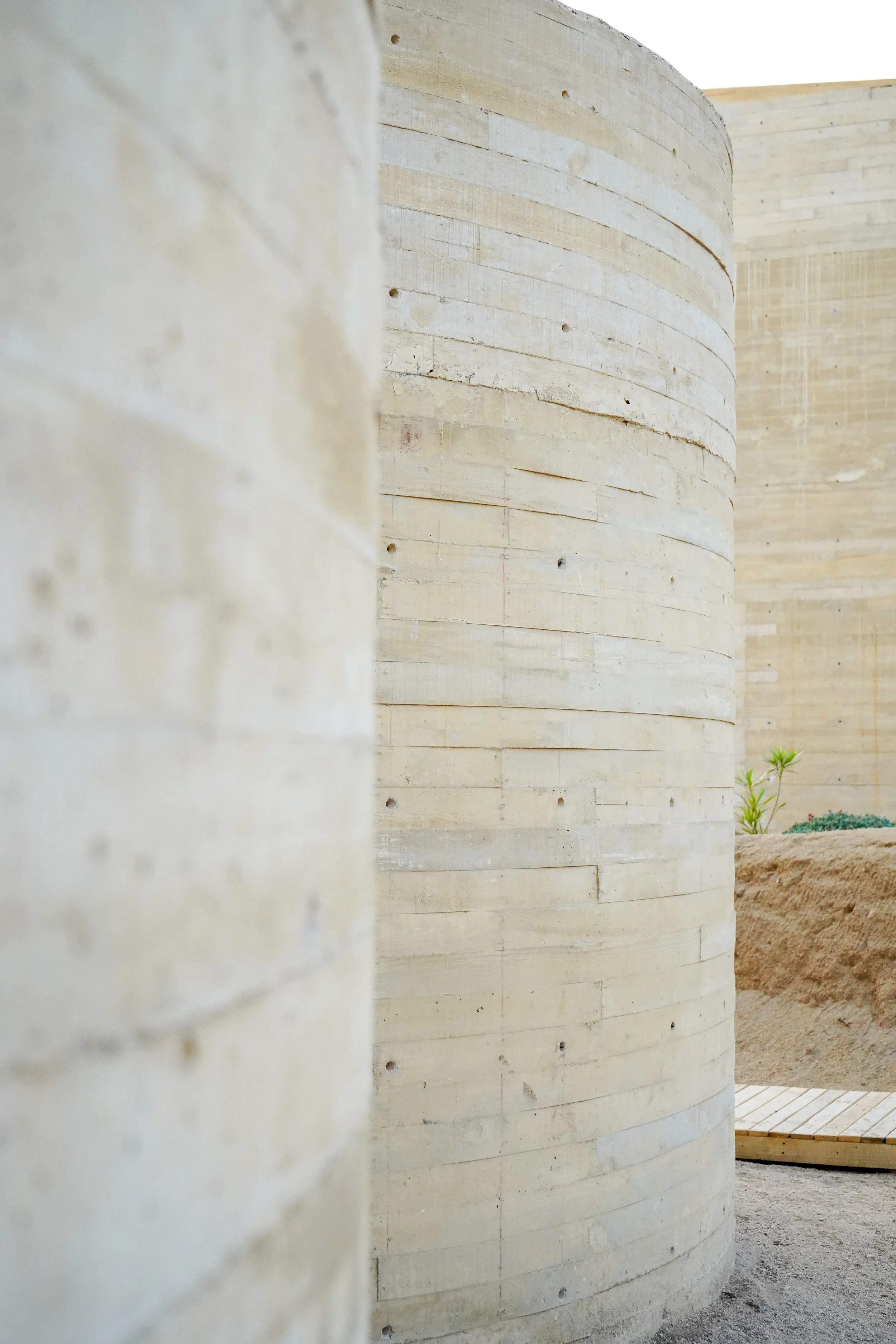 Close-up of curved, light-colored wooden walls with visible grain and nails, part of an outdoor structure.