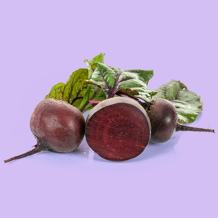 Three beets with green leaves on a light purple background, one beet cut in half showing deep red interior.