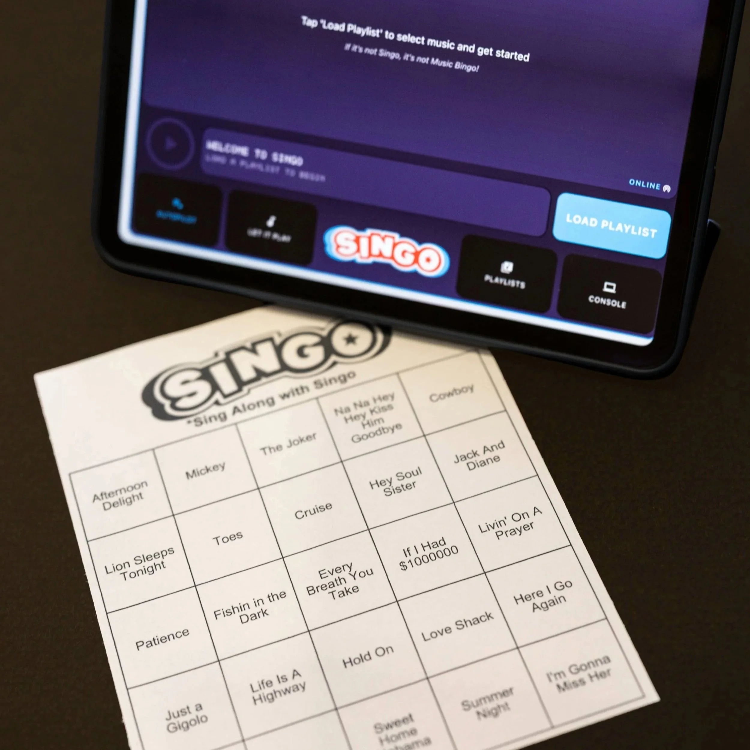Singo musical bingo game with tablet interface and bingo card, showcasing interactive DJ entertainment options like trivia and karaoke by DJ Bam