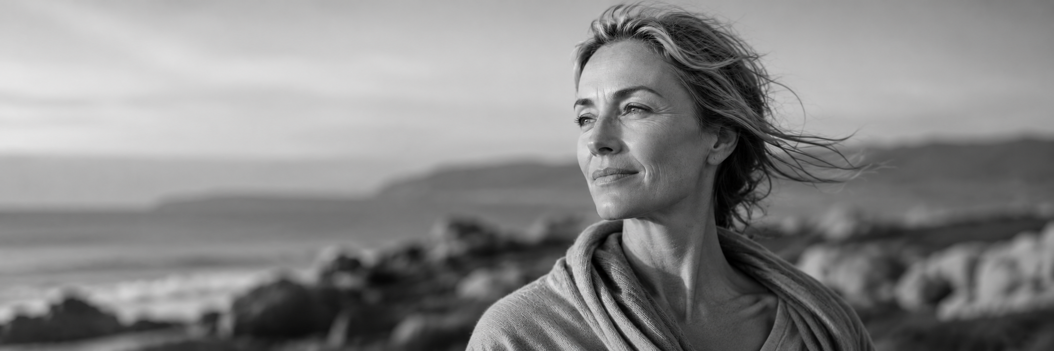 Black and white portrait of a woman in midlife looking toward the horizon, symbolizing healthy aging, skin health, longevity, and resilience.