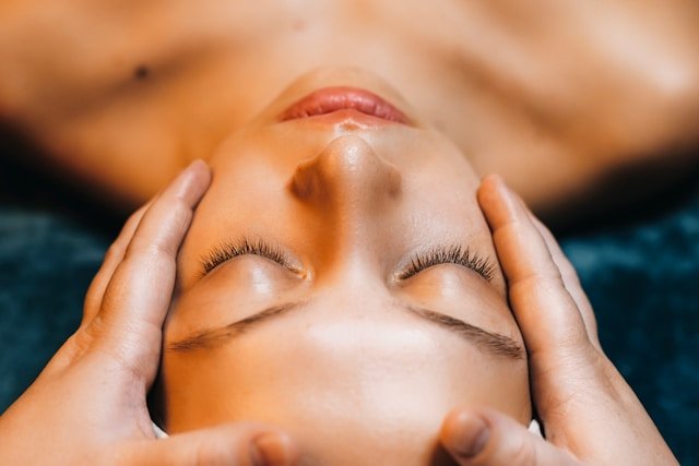 Close-up of a person receiving a massage on their forehead and temples.