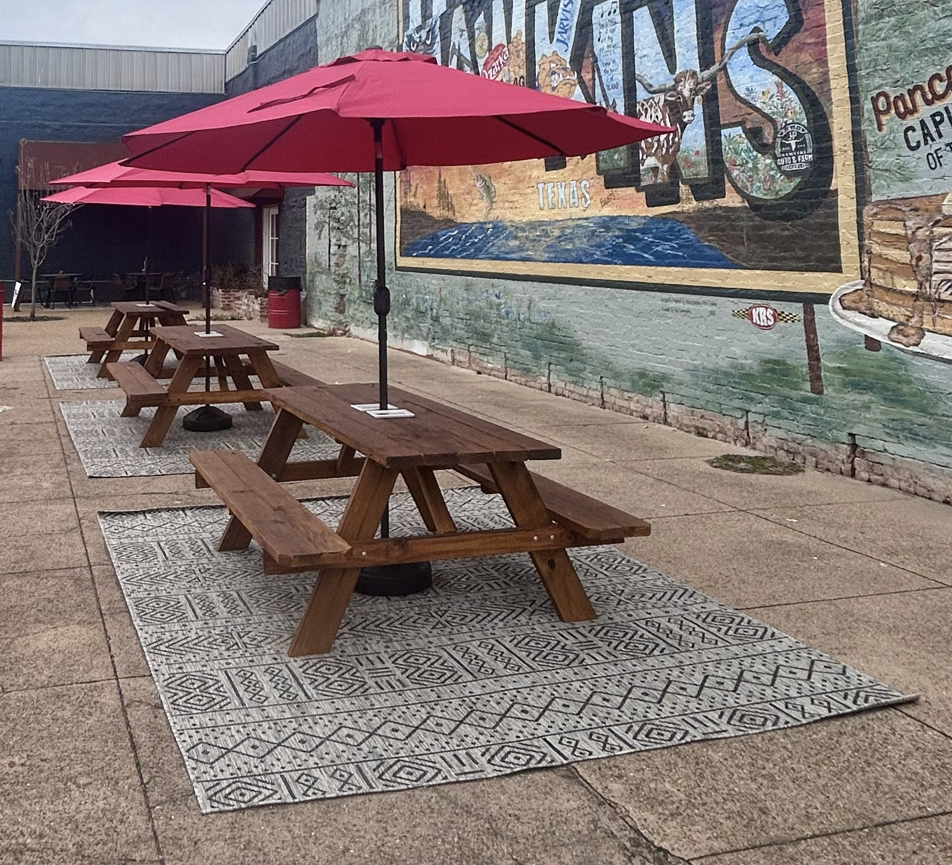 Picnic tables with shade in front of the Hawkins mural in East Texas' own Hawkins, TX.
