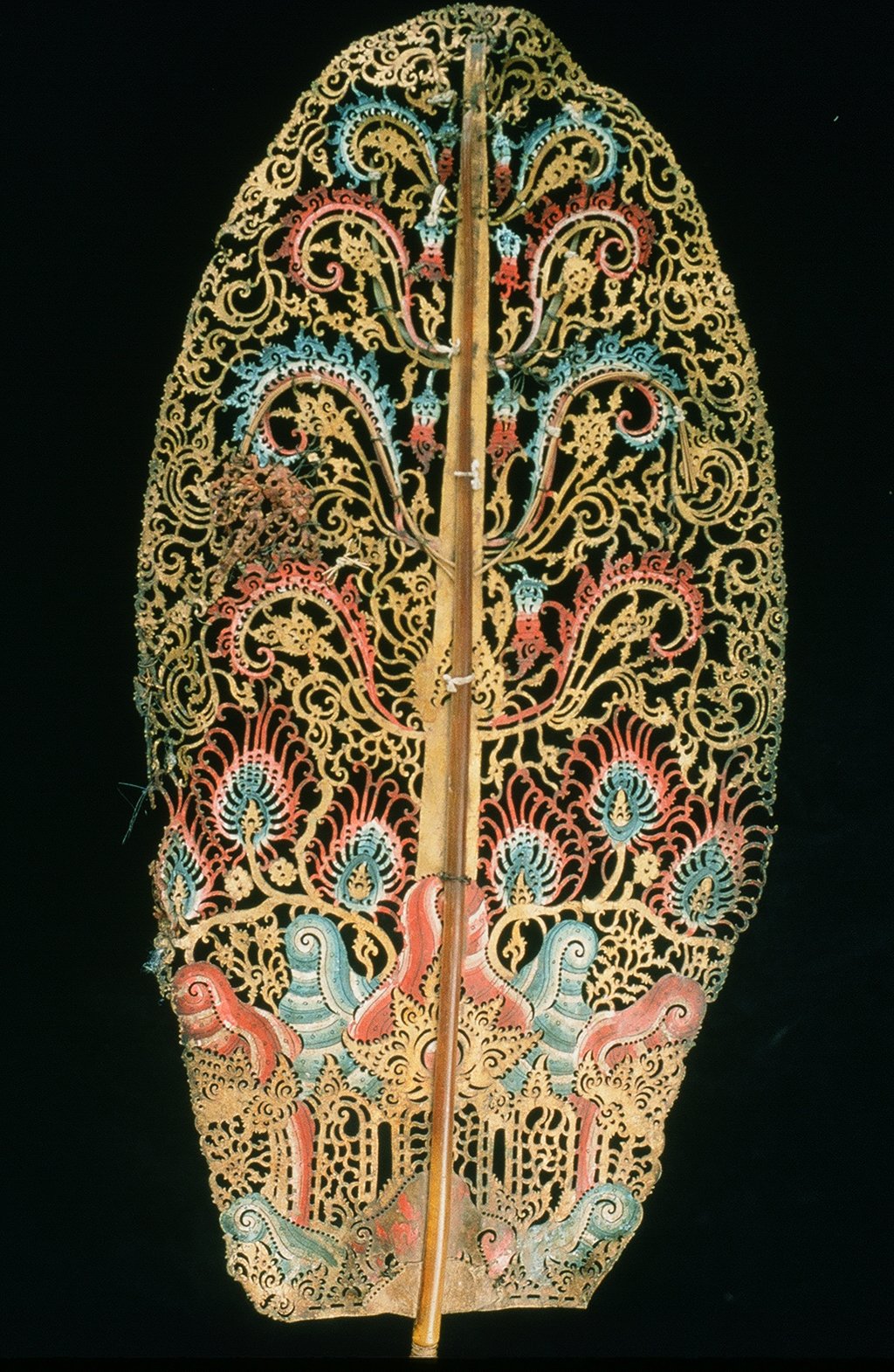 Intricately carved and painted decorative wooden leaf with floral and swirl patterns on black background.