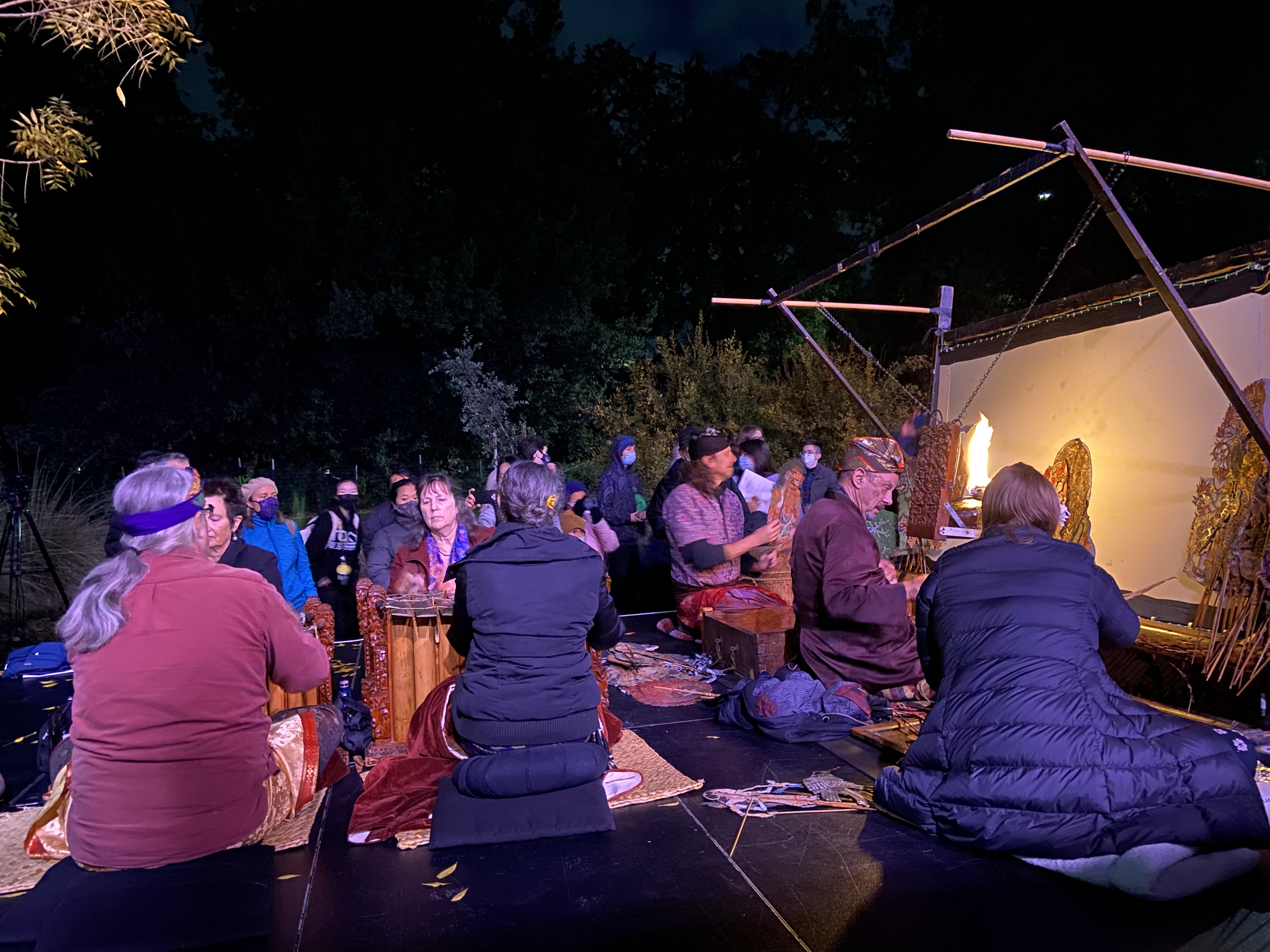 People participating in a ritual or prayer around a fire and altar at night.