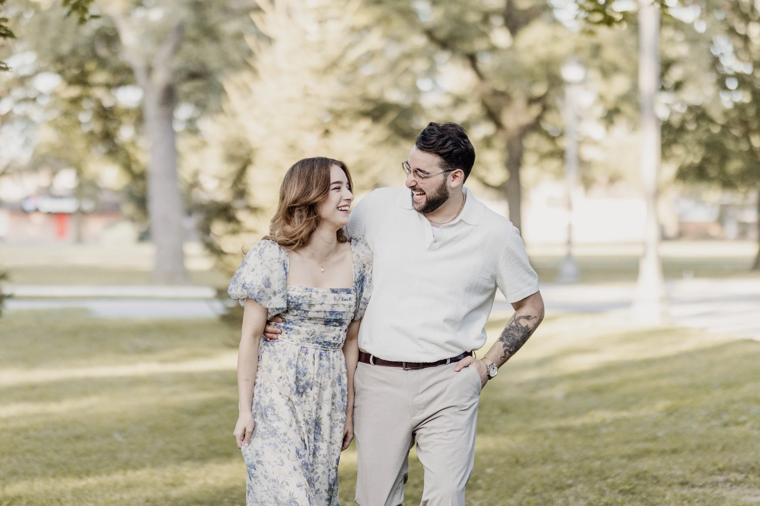 A couple walking together in a park, smiling and looking at each other.