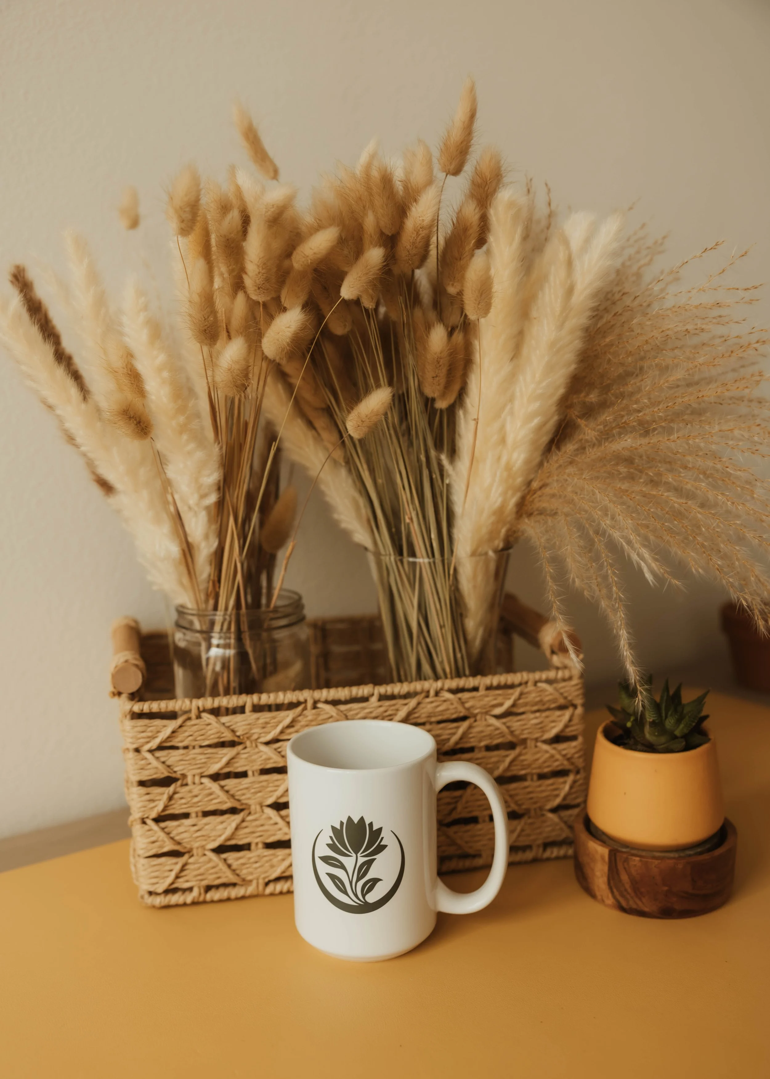 Decorative pampas grass, natural textures, and an R&R mug styled in a warm, calming space that reflects the grounded, holistic approach of Root & Rhythm Holistic Care and intentional everyday wellness.