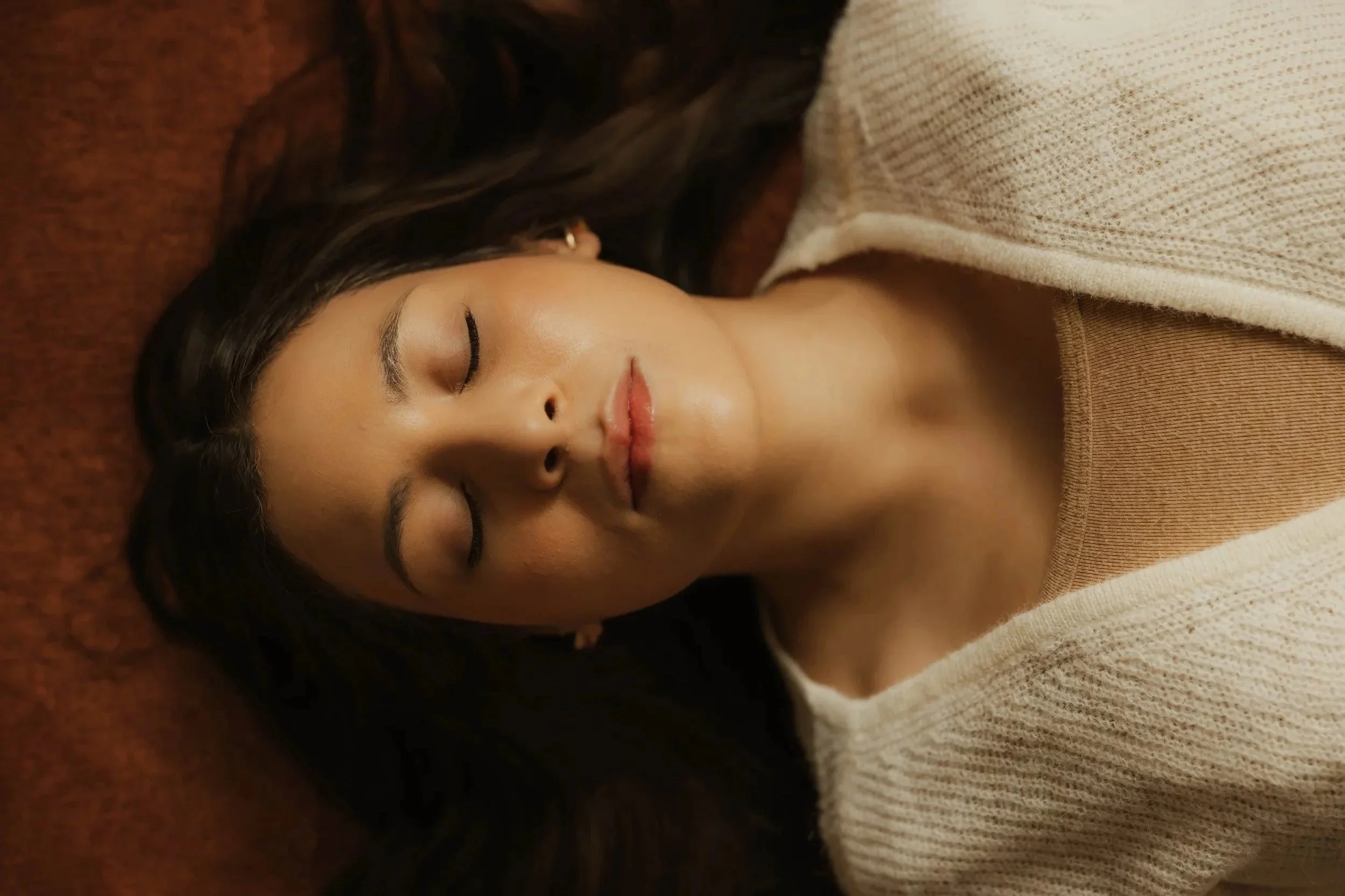 Close-up of a mother resting with eyes closed in a calm, grounding moment that reflects emotional wellness, nervous system restoration, rest, and holistic postpartum support through Root & Rhythm Holistic Care.