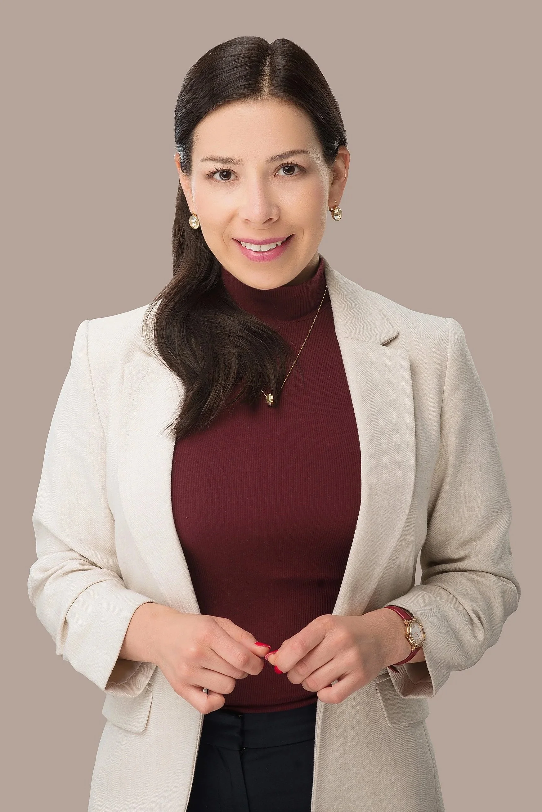 Fotografía profesional en estudio, persona de medio cuerpo con ligera sonrisa, fondo beige y vestimenta casual.