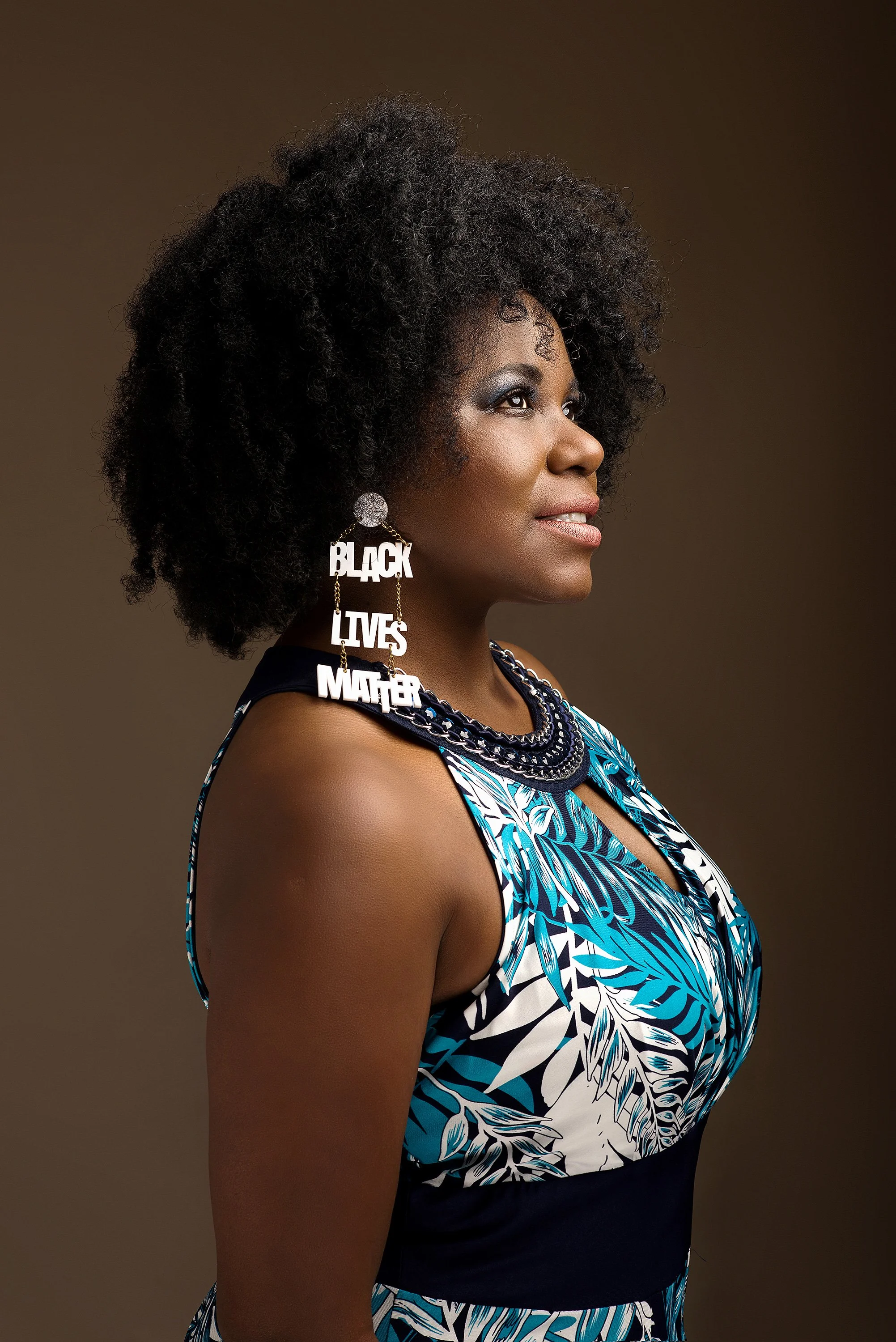Retrato en estudio de Sofía Carrillo, activista afroperuana, con expresión firme y serena. Lleva un arete de Black Lives Matter, símbolo que refuerza su compromiso con la justicia racial y los derechos humanos. Una imagen que transmite identidad, fue