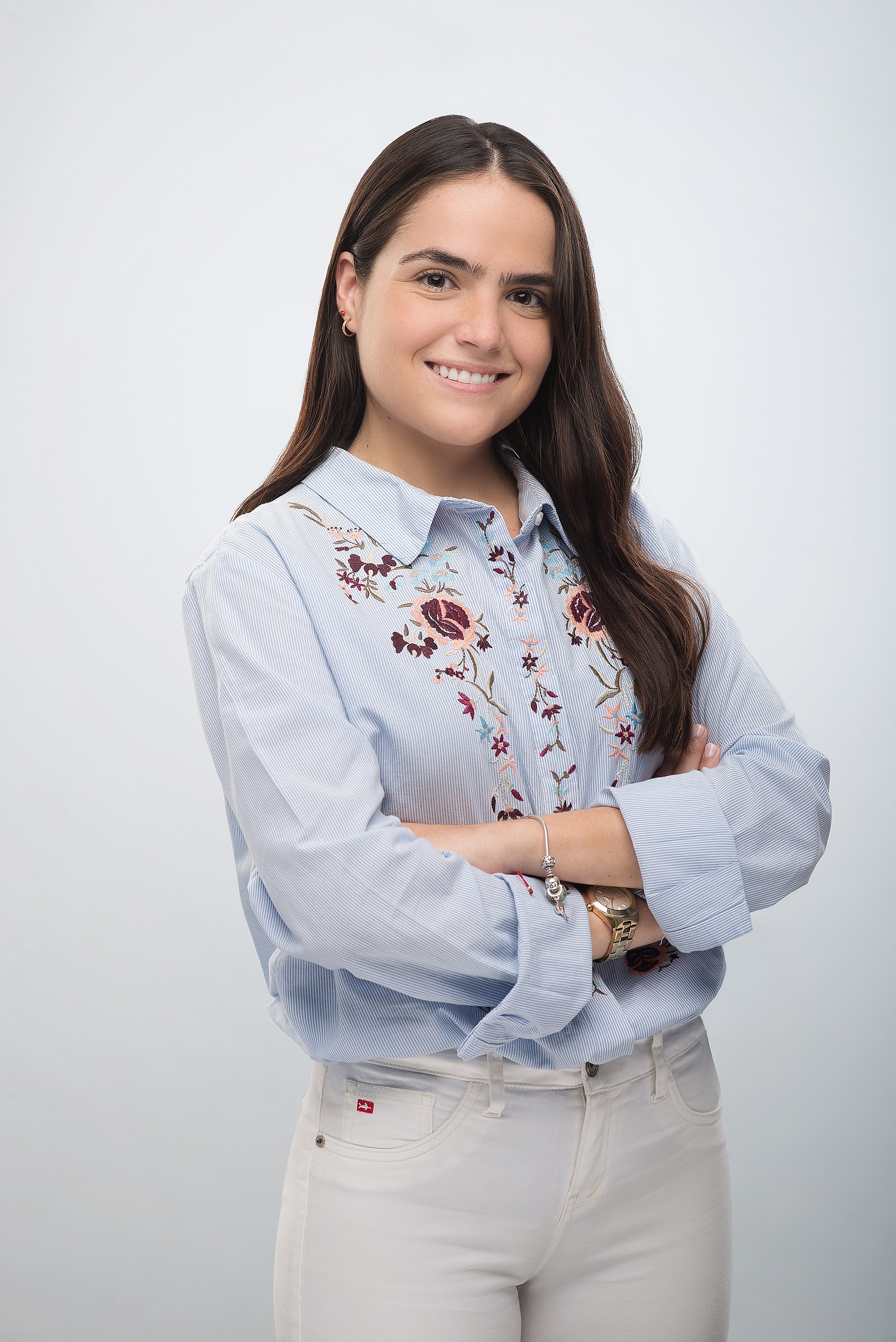 Fotografía en estudio de estilo profesional, con pose ligeramente creativa, como brazos cruzados o sonrisa sutil.