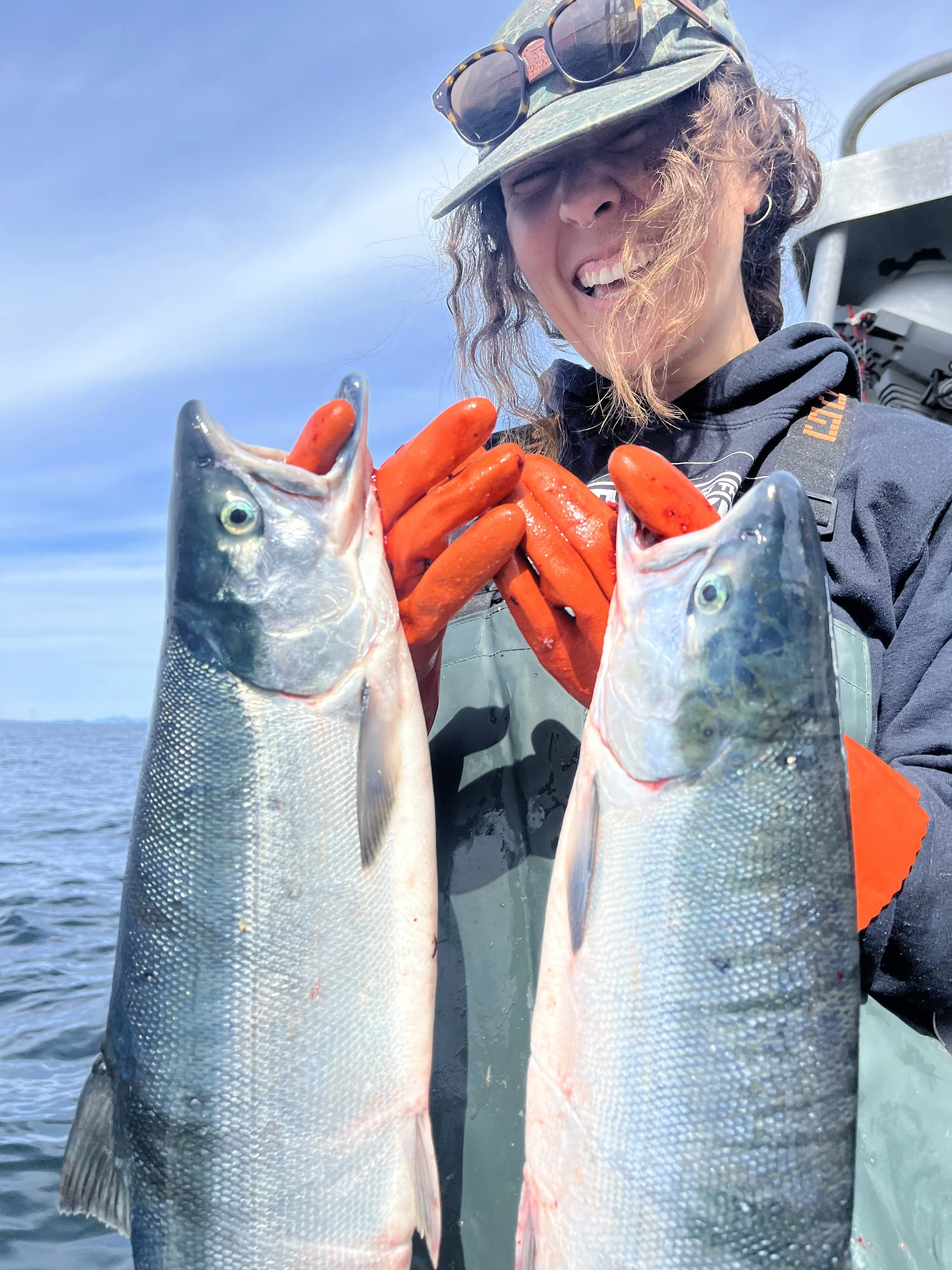 Girl holding two Alaskan salmon on the deck of a commercial fishing boat
