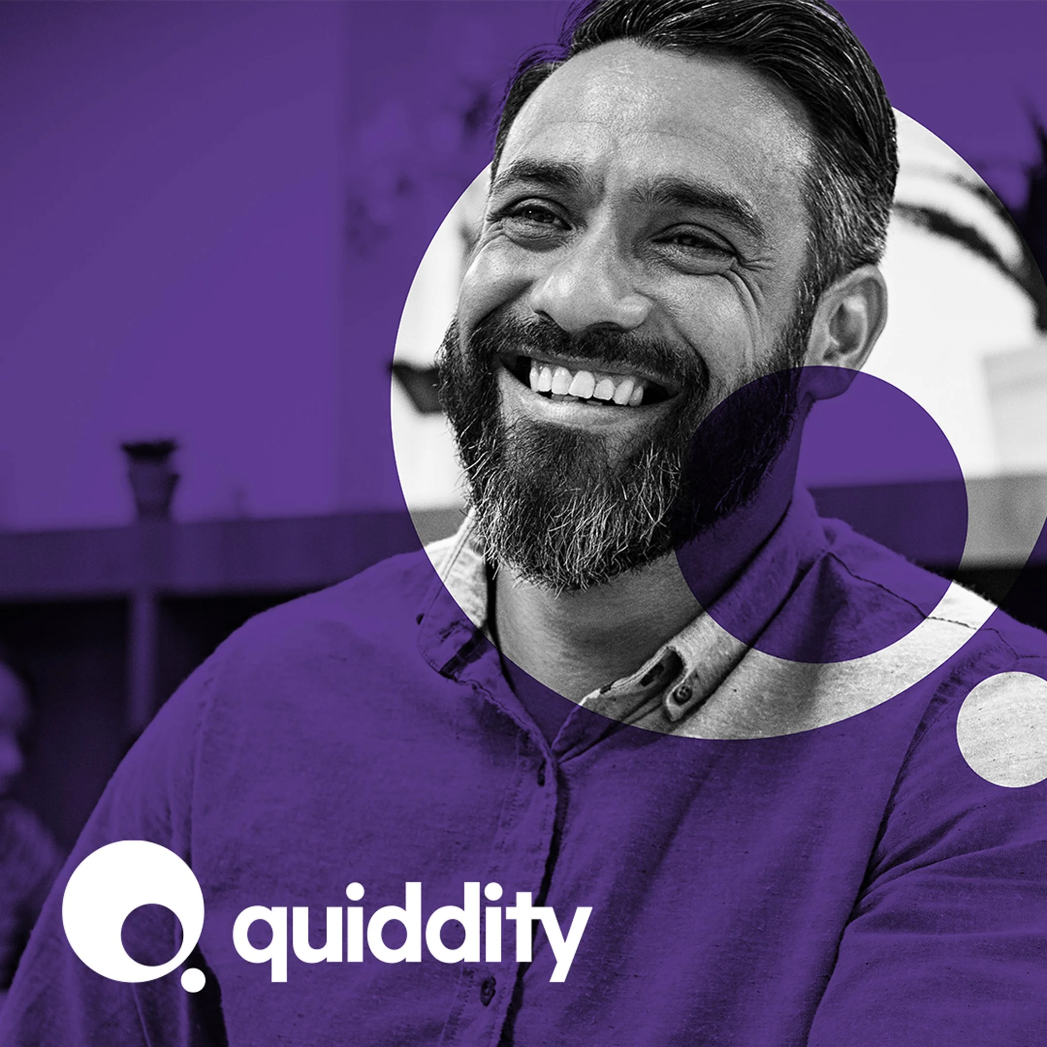 A smiling man with a beard and short hair, wearing a button-up shirt, in a black-and-white photo with purple graphic overlays and the white 'quiddity' logo.
