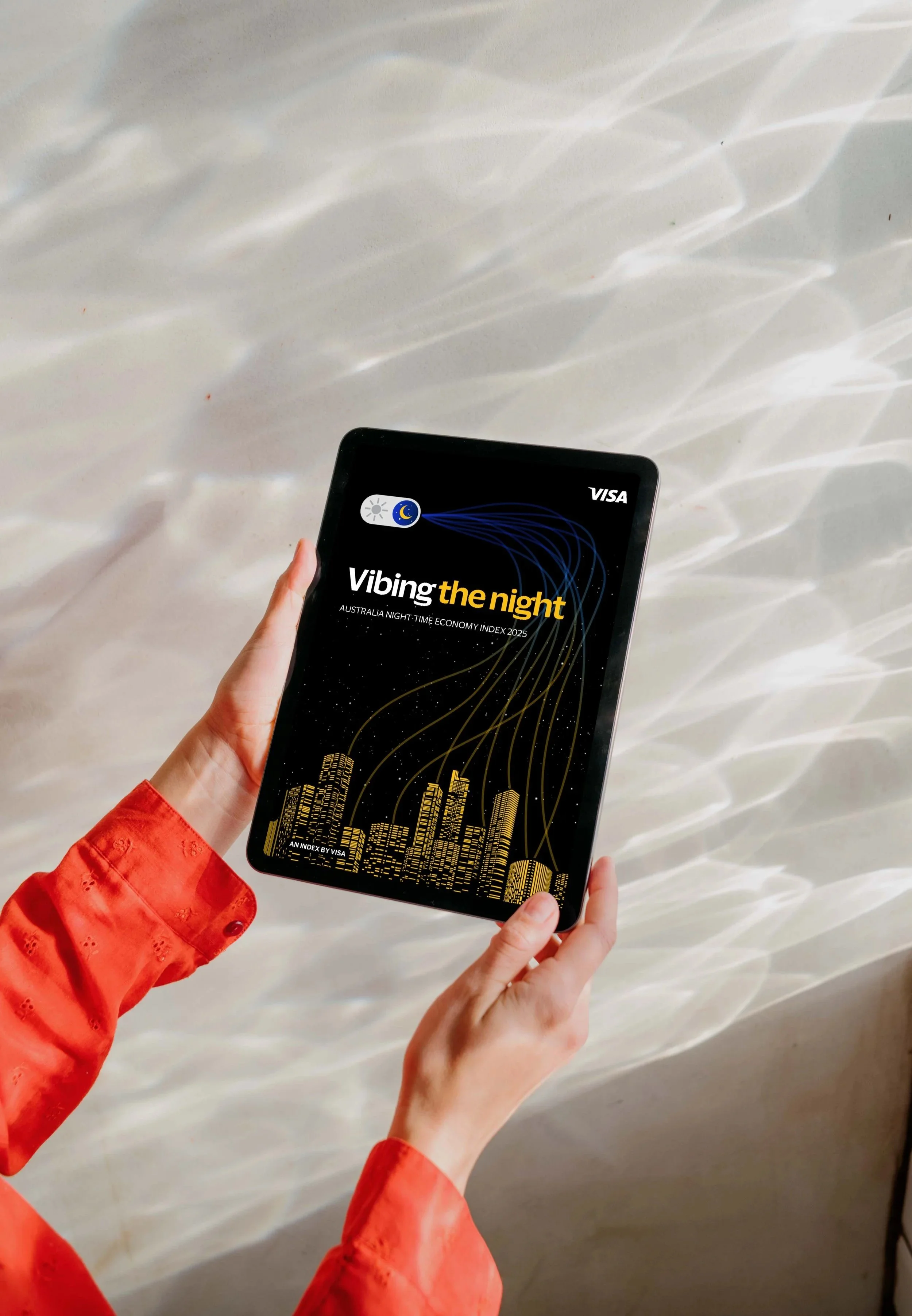 Person holding a tablet displaying an Australian night-time economy index report, with a city skyline graphic and a stylized moon and cloud icon on a dark background.