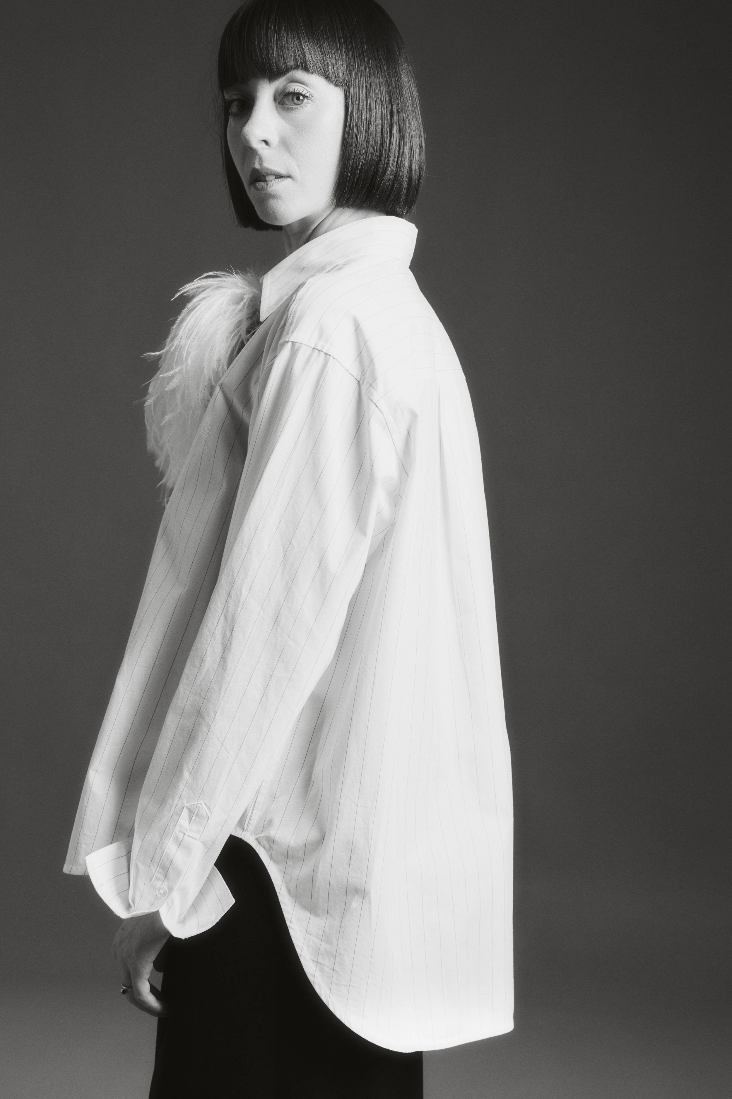 Black-and-white portrait of Sophie Valenti wearing an oversized striped shirt and dark trousers.