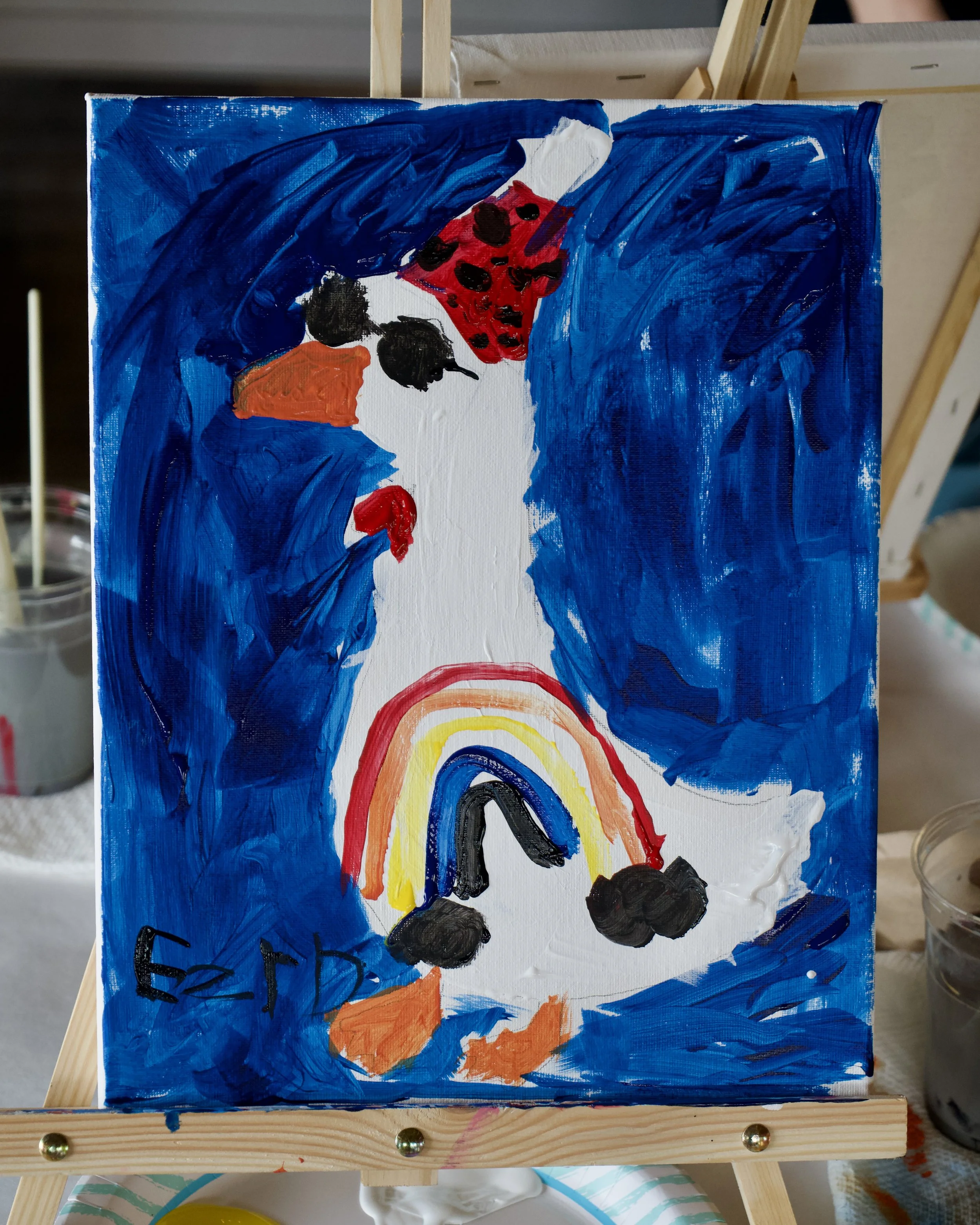 Close up of a goose painting with a blue background and sunglasses and a rainbow