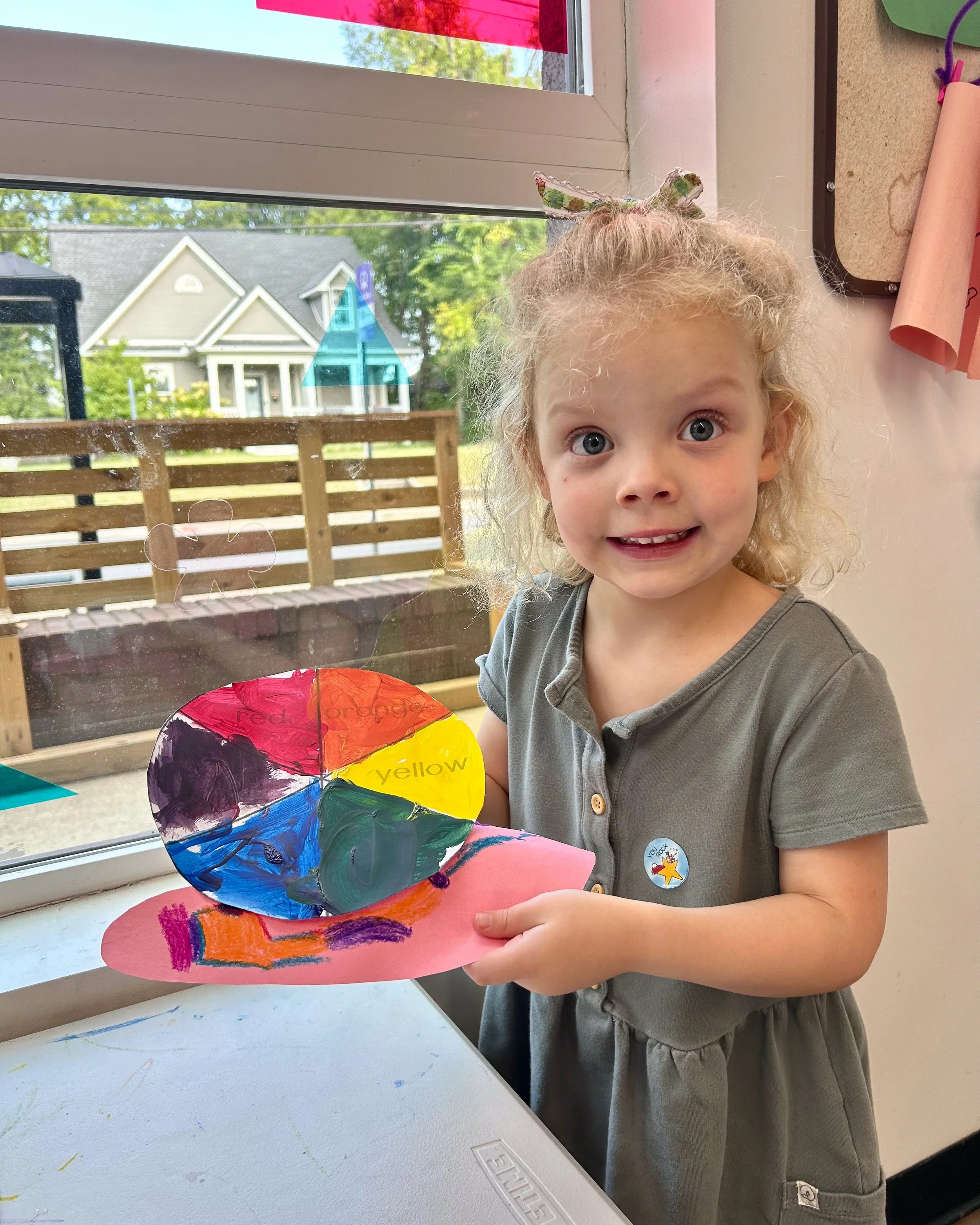 A little girl smiles for the camera and holds up her color wheel snail