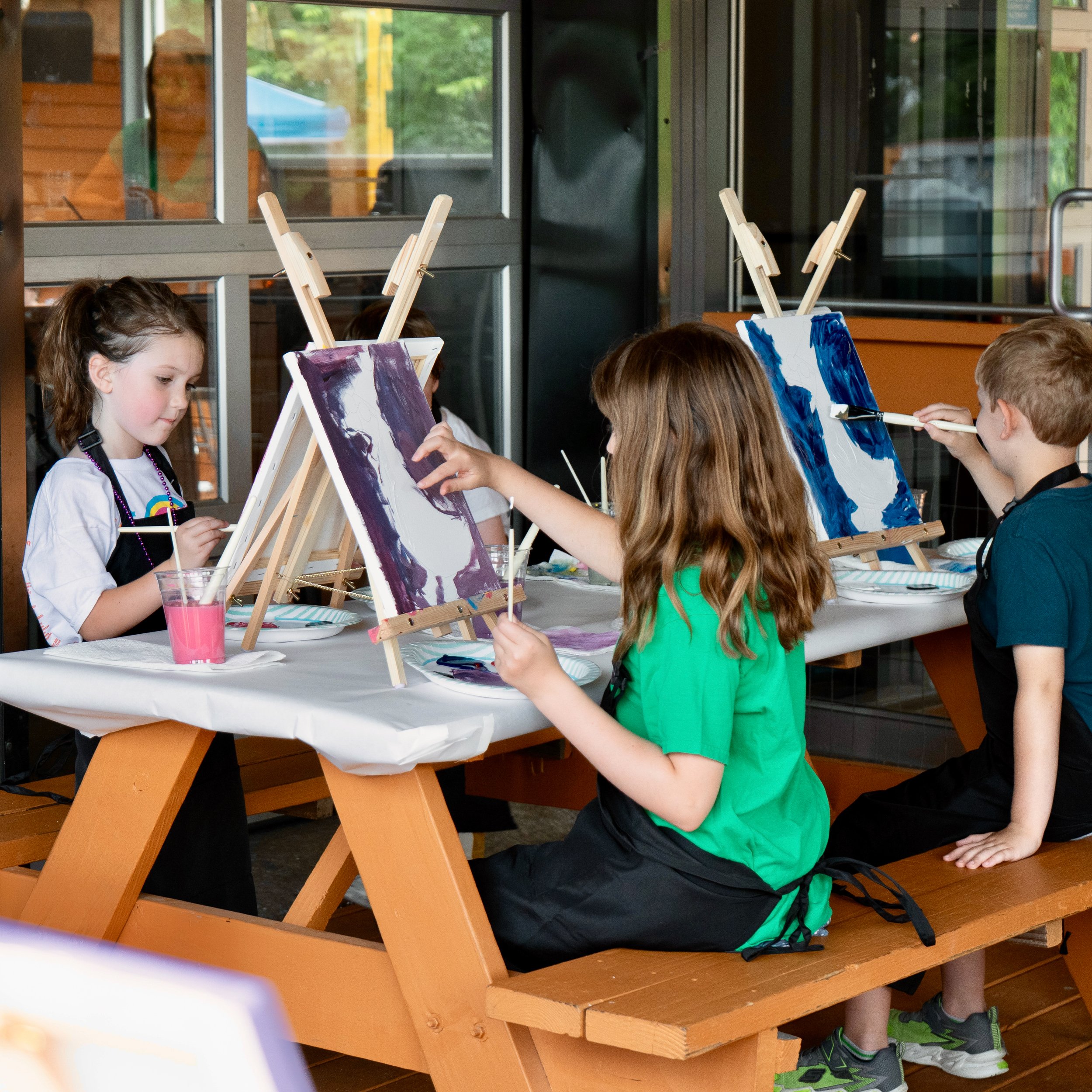Small group of three kids at a table painting together