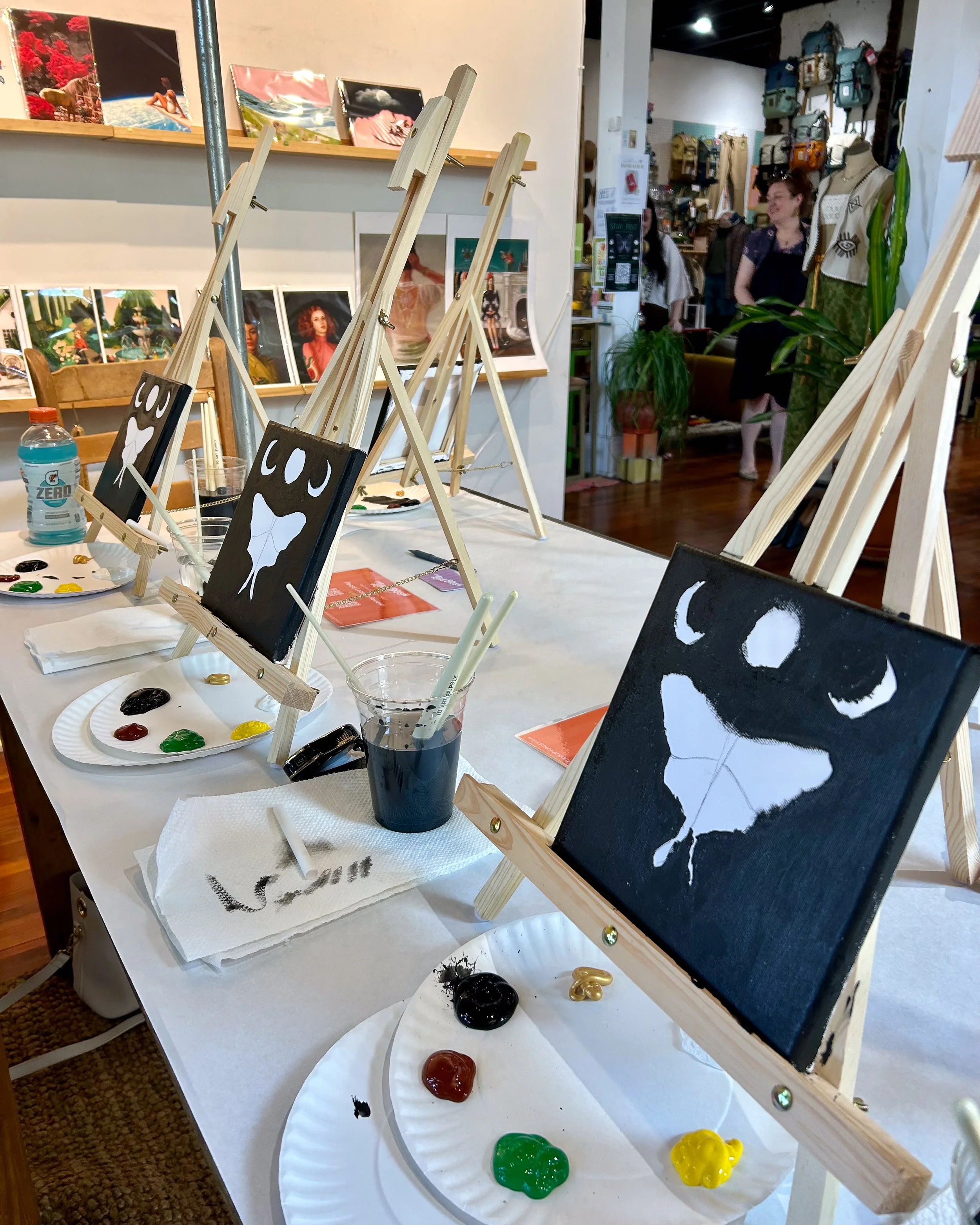 Luna moth paintings in progress on easels in an eclectic Nashville shop