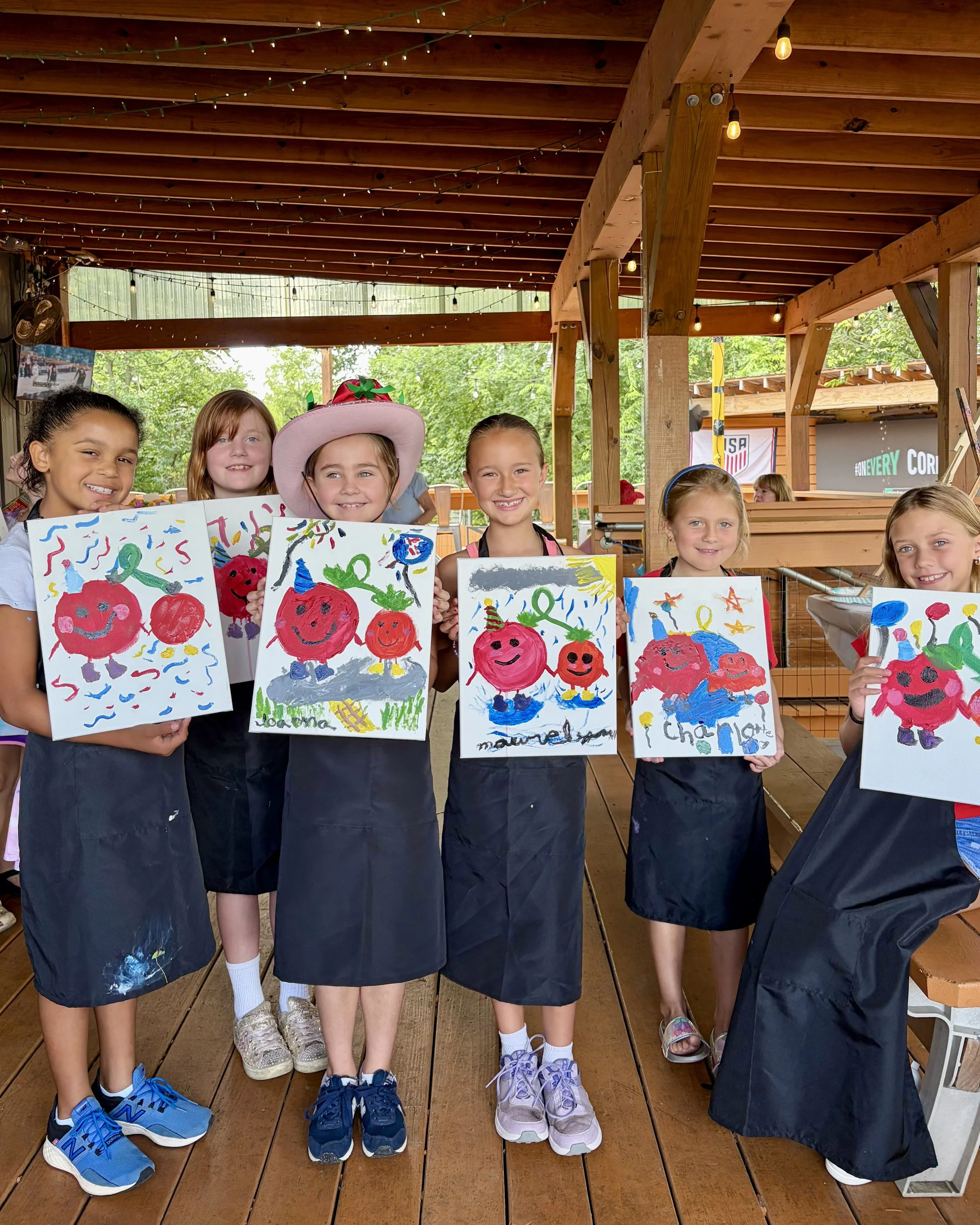 Group of little girls standing with their tomato paintings on display
