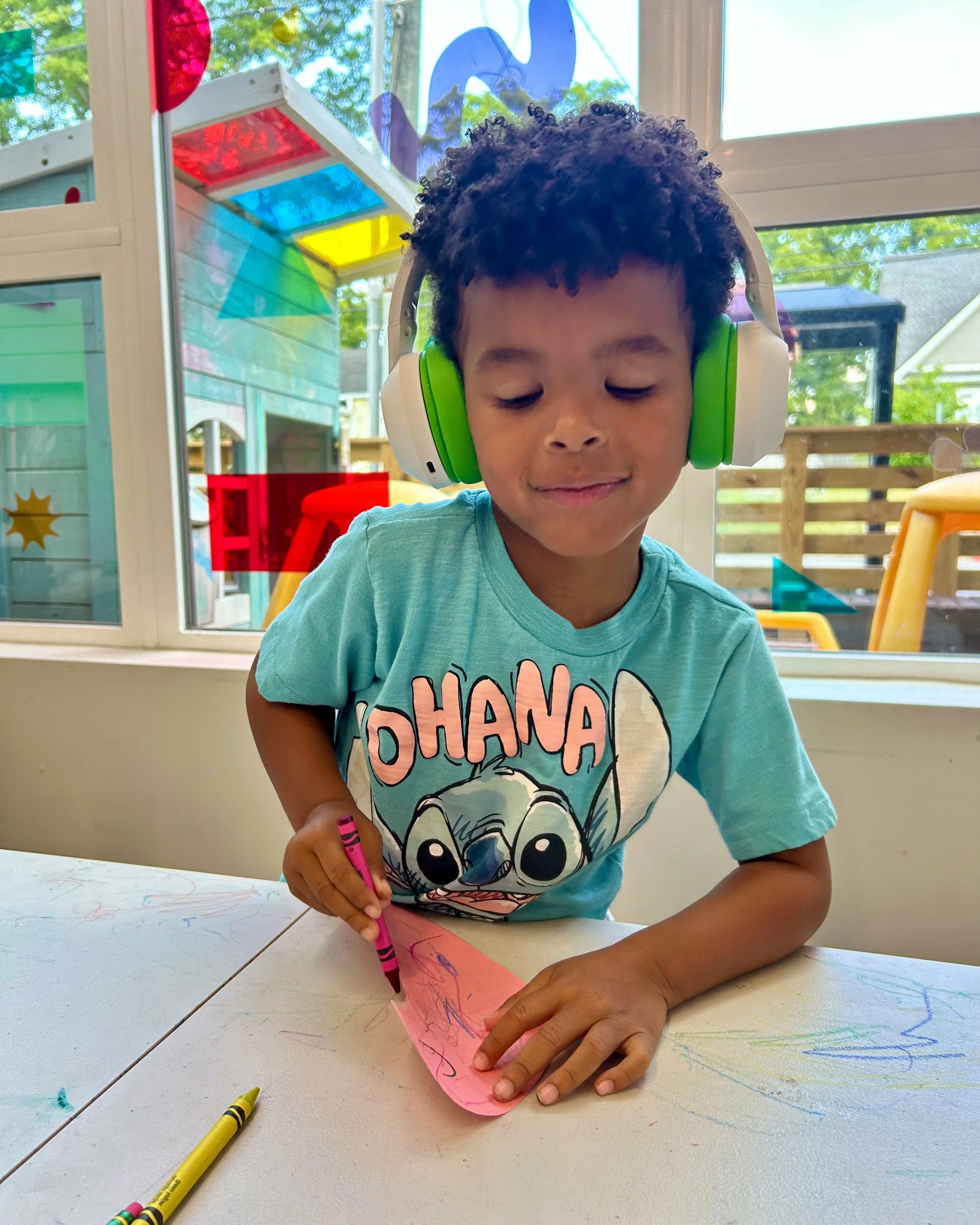 A little boy with headphones and a Lilo and Stitch shirt making a color wheel snail