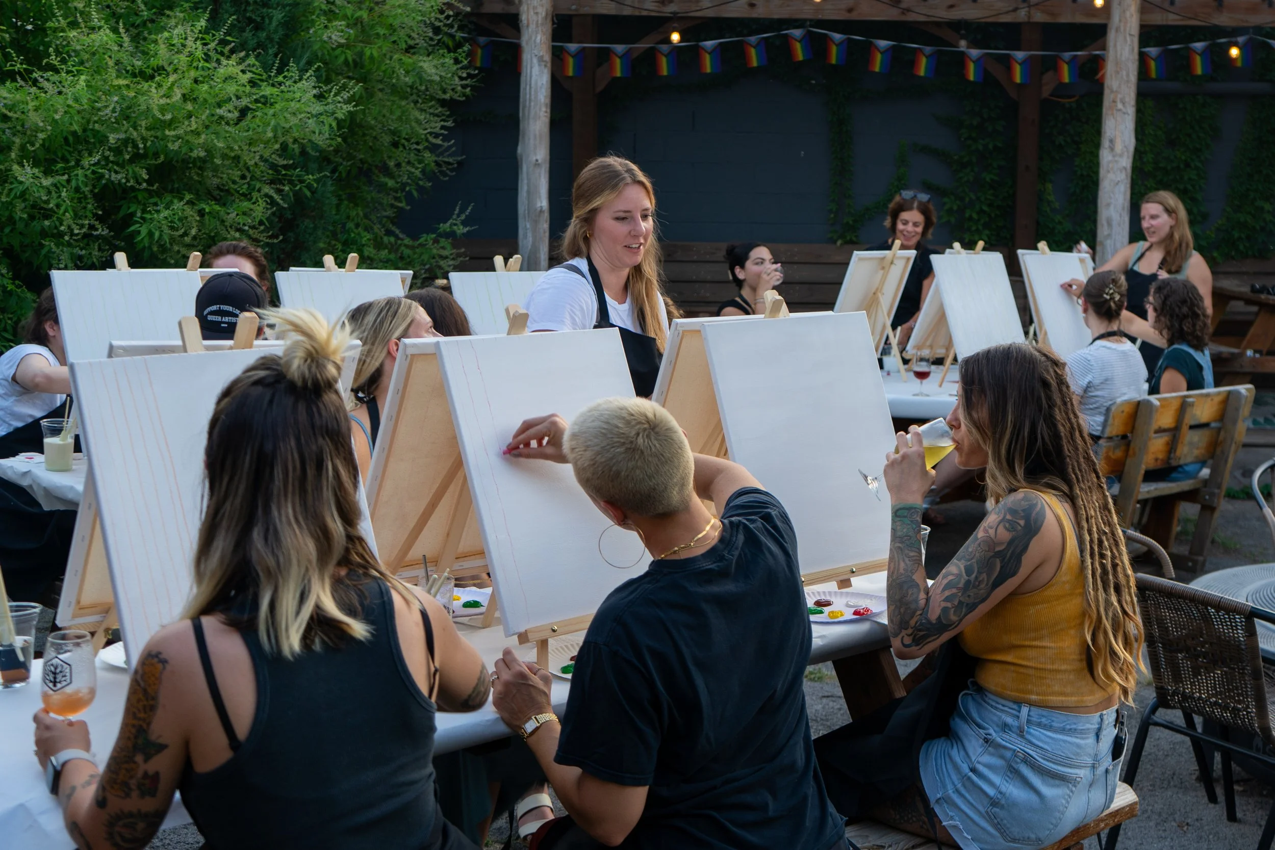 A group of people paints and drinks outside in a courtyard