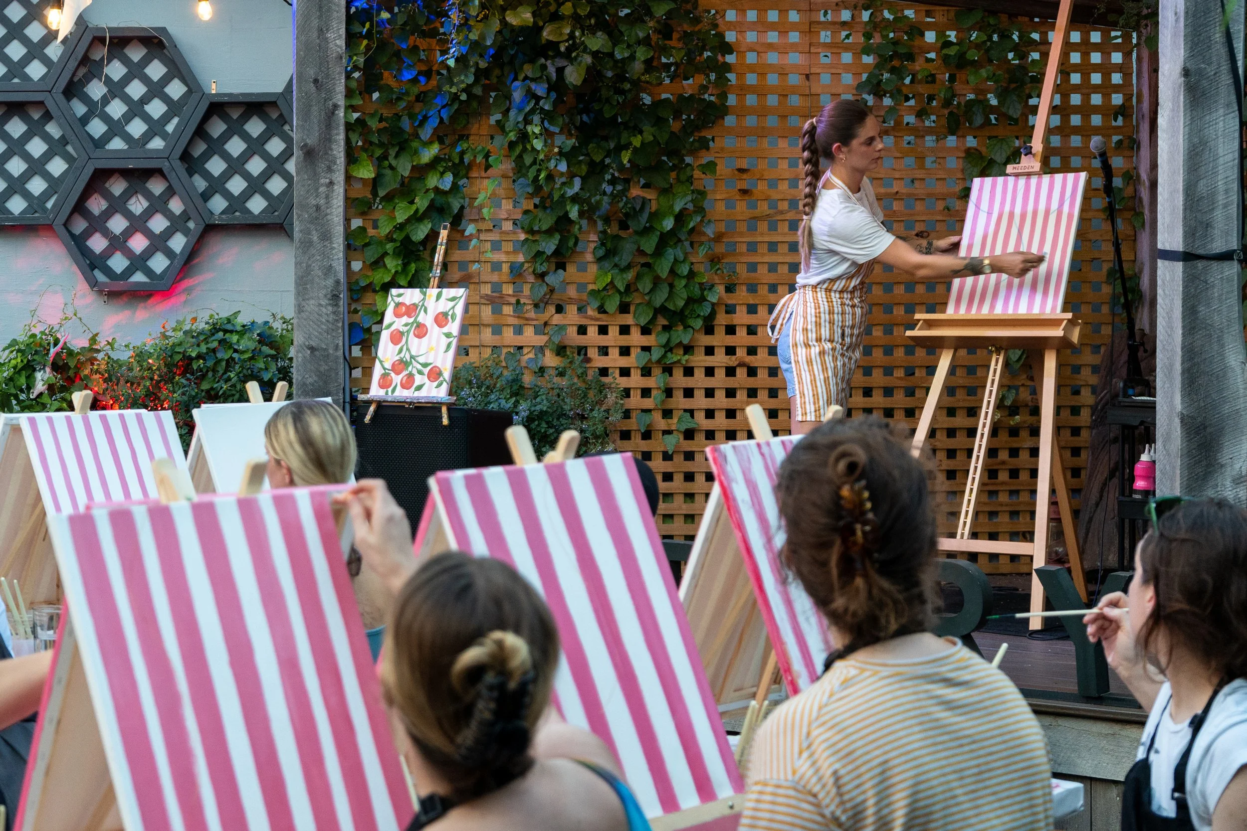 Art instructor on stage teaching a class with striped paintings