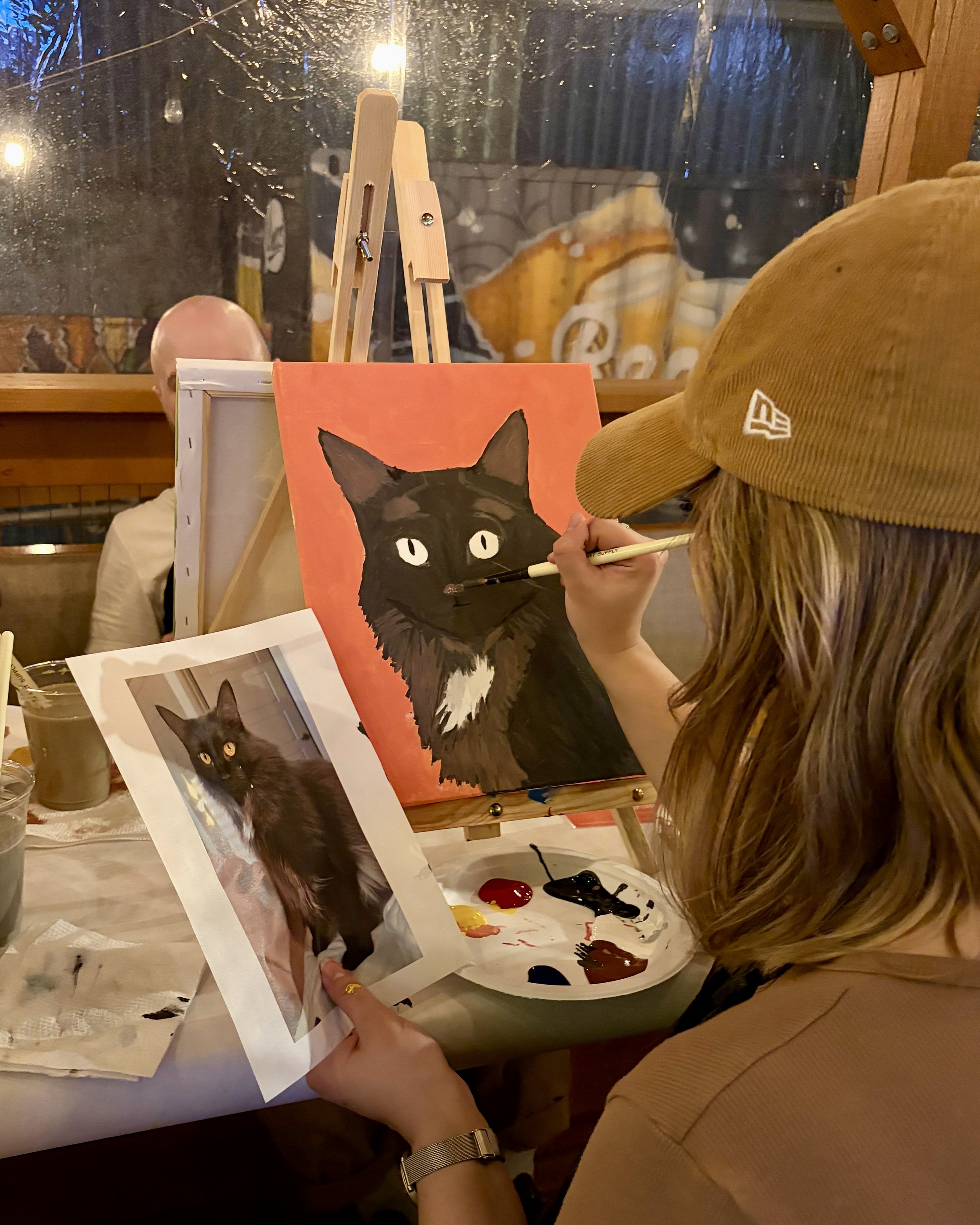 A girl paints a black cat with an orange background