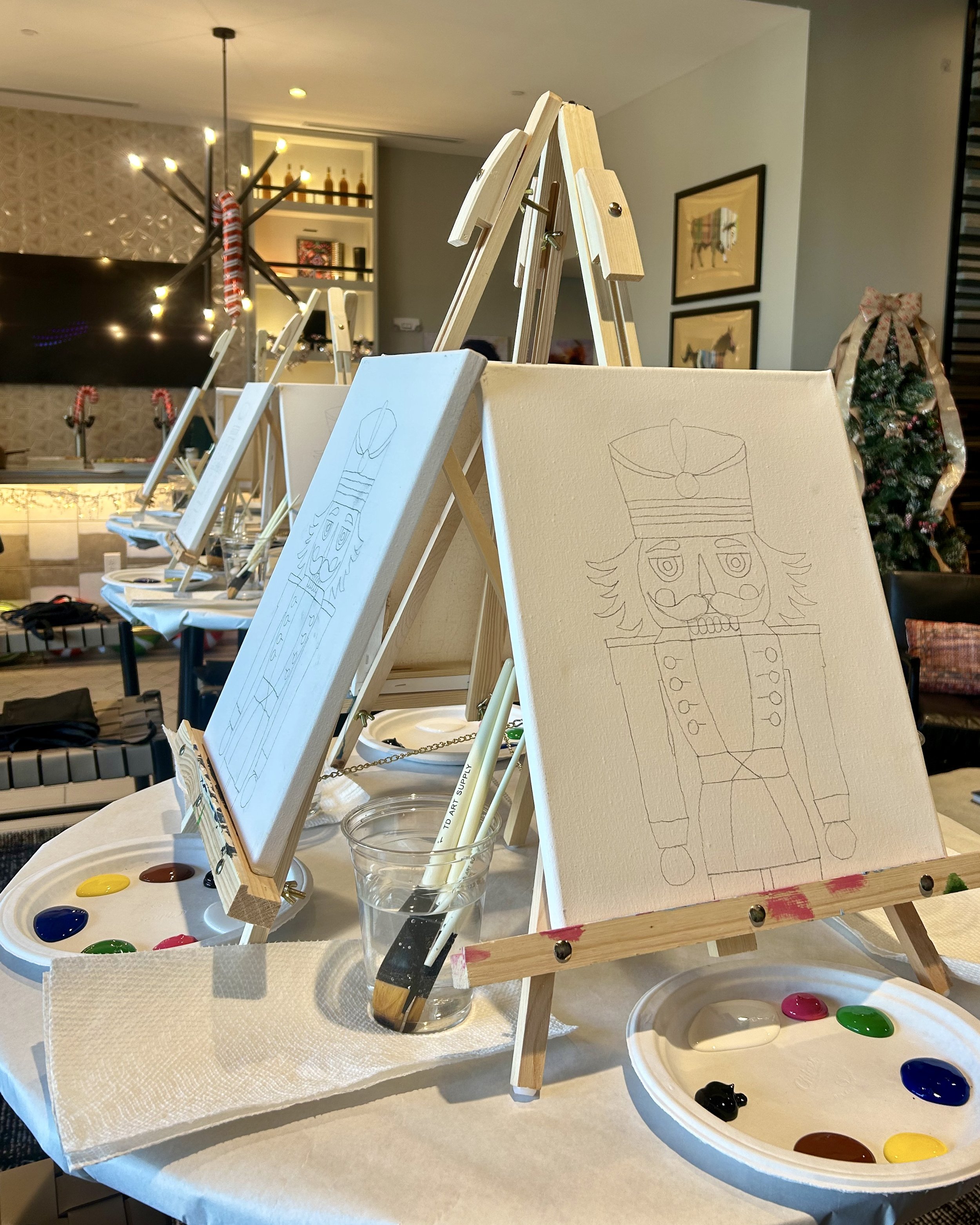 Canvases with sketched out drawings and fresh paint on paper plates