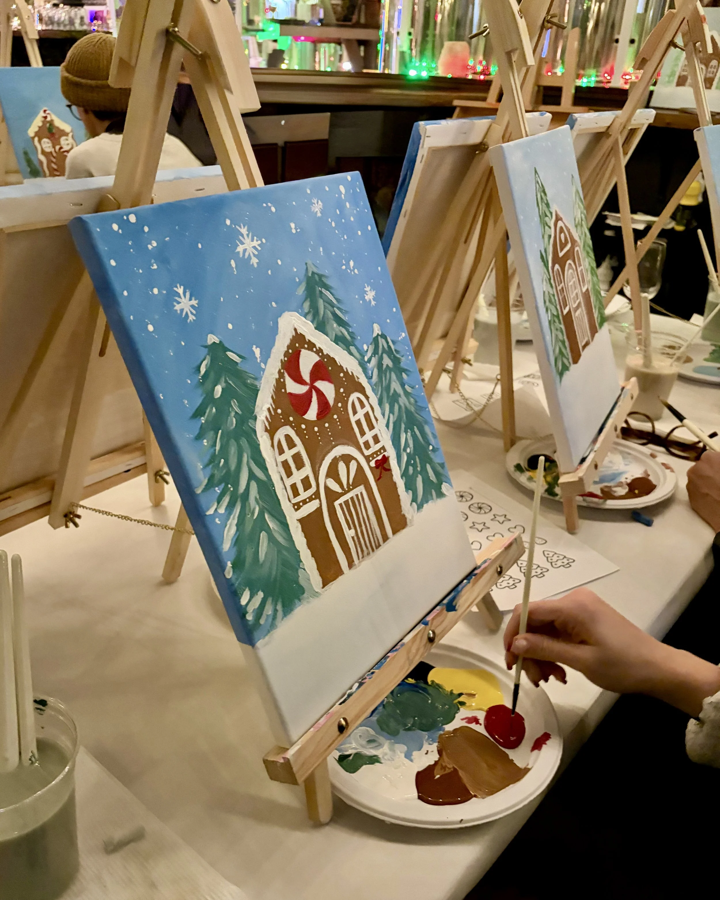 Up close photo of someone painting a gingerbread house on canvas