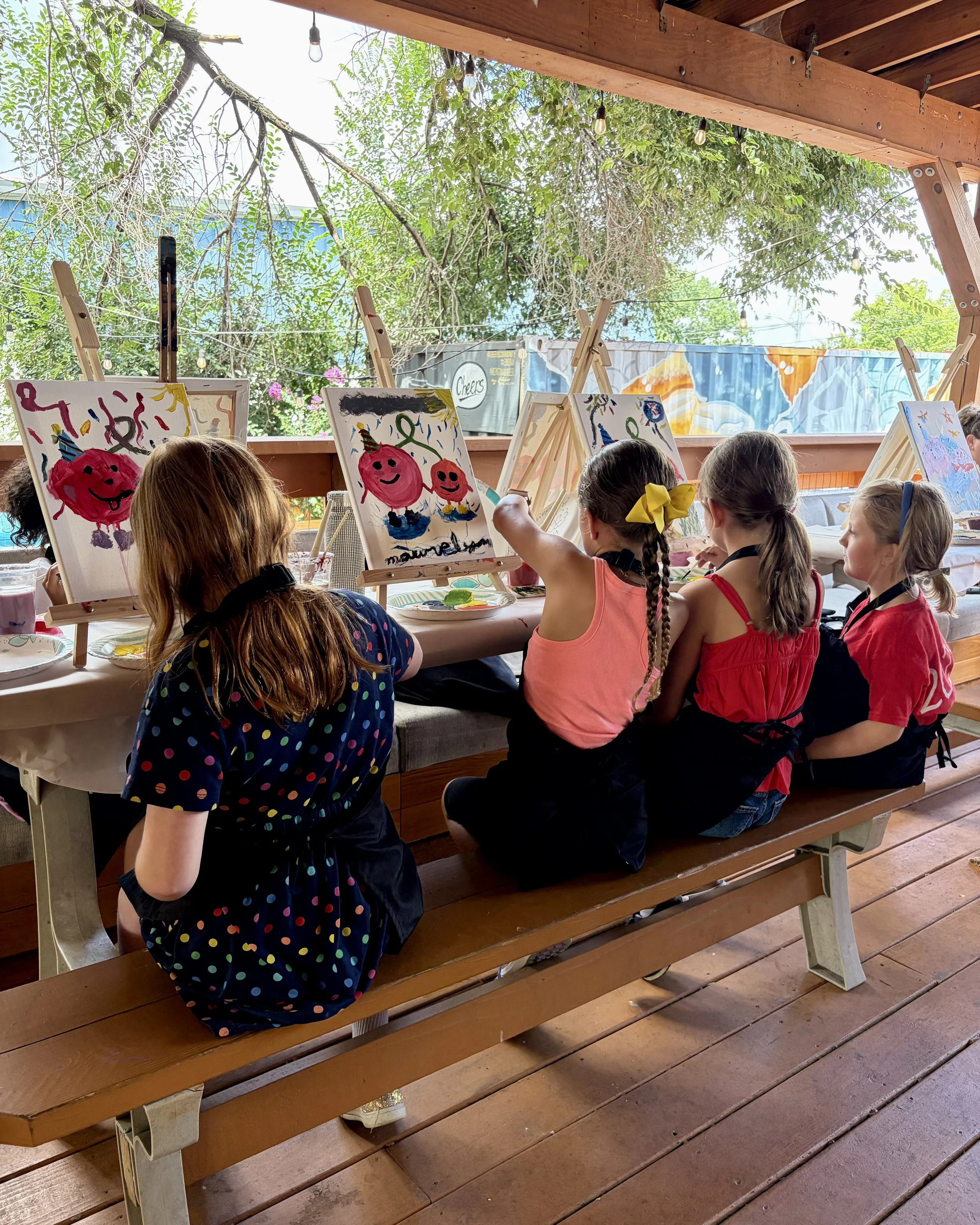 Group of girls painting tomatoes together on a patio
