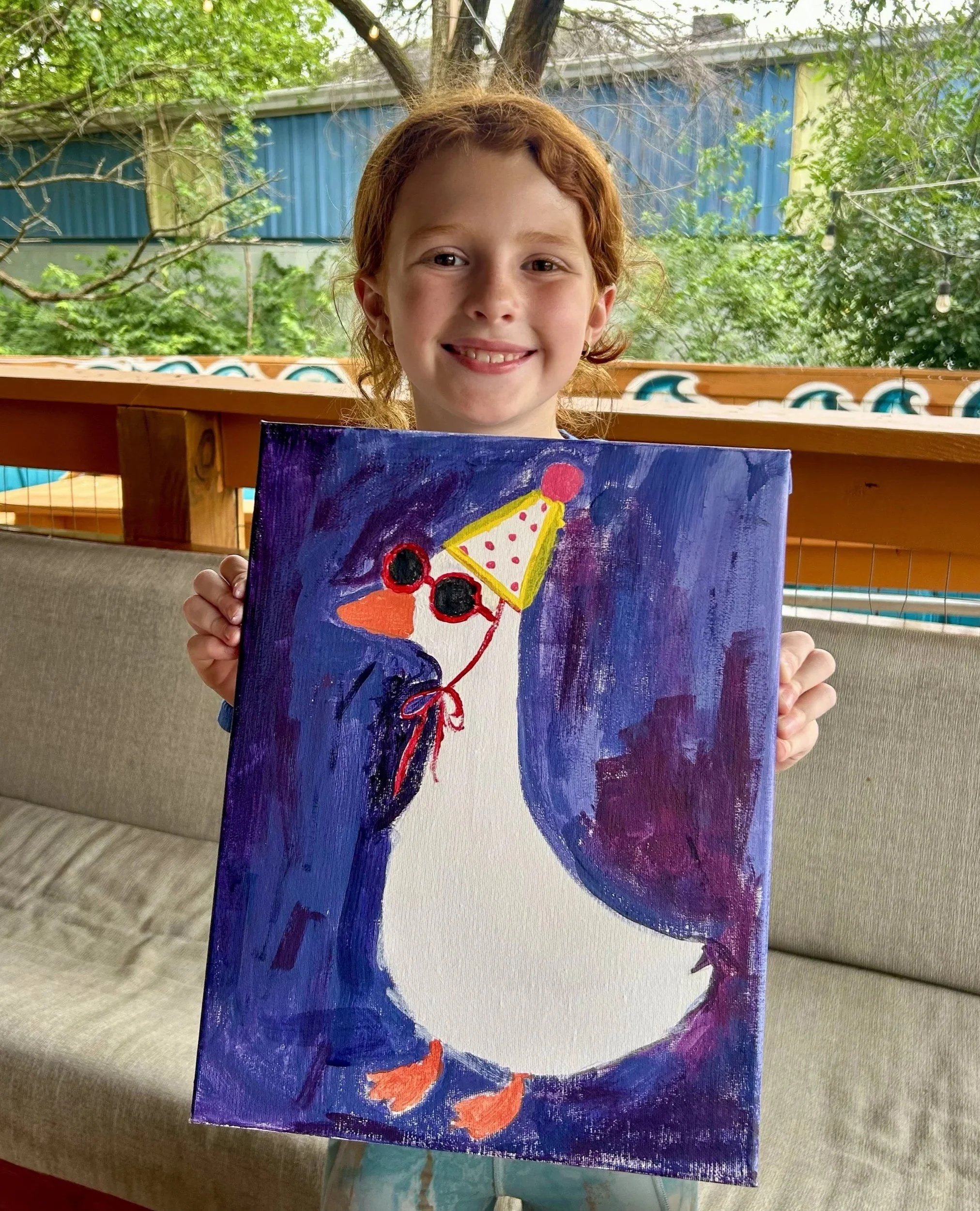 Young girl holding up painting she created smiling