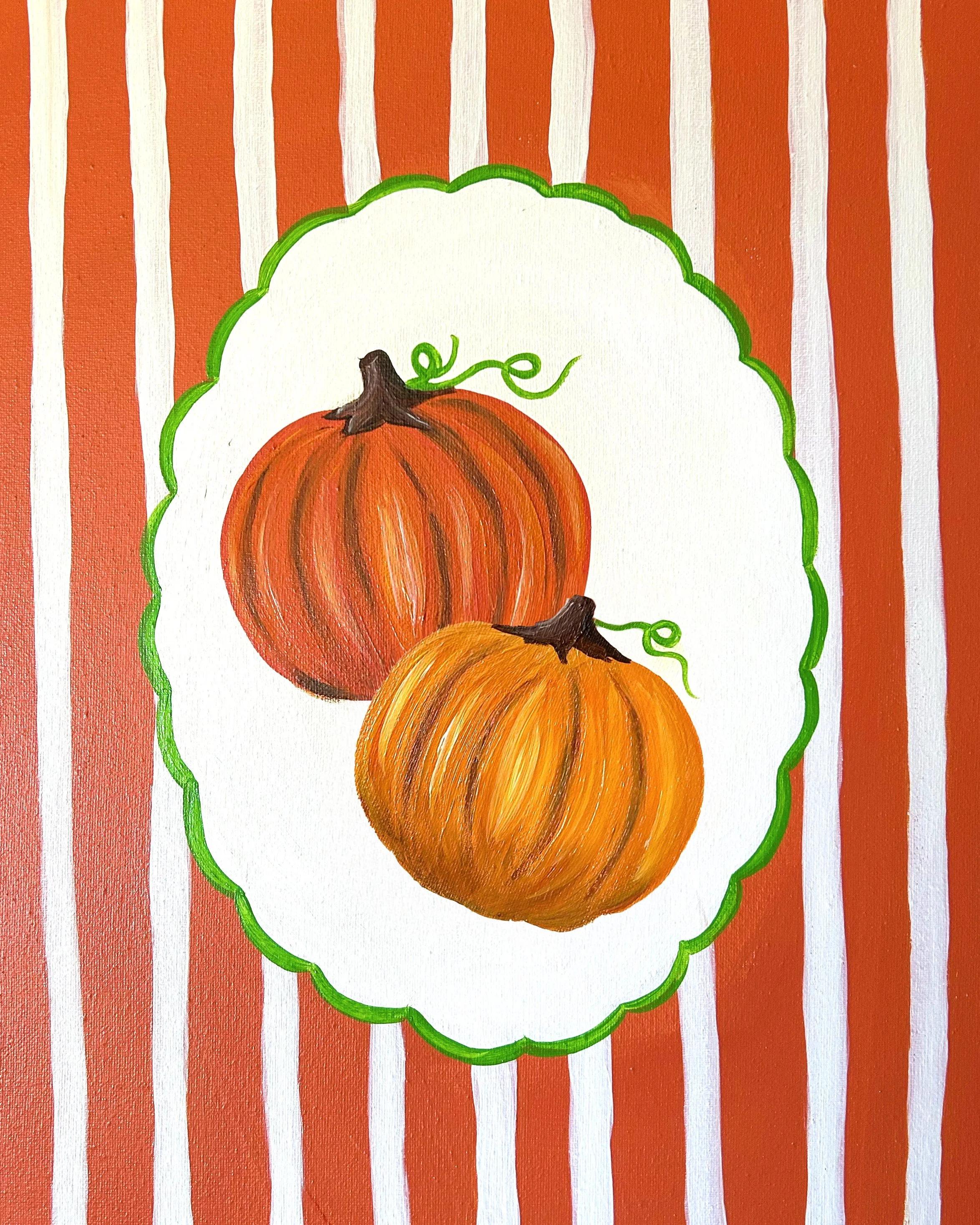 Up close photo of two orange pumpkins in a white scalloped circle with green trim and orange stripes in the background