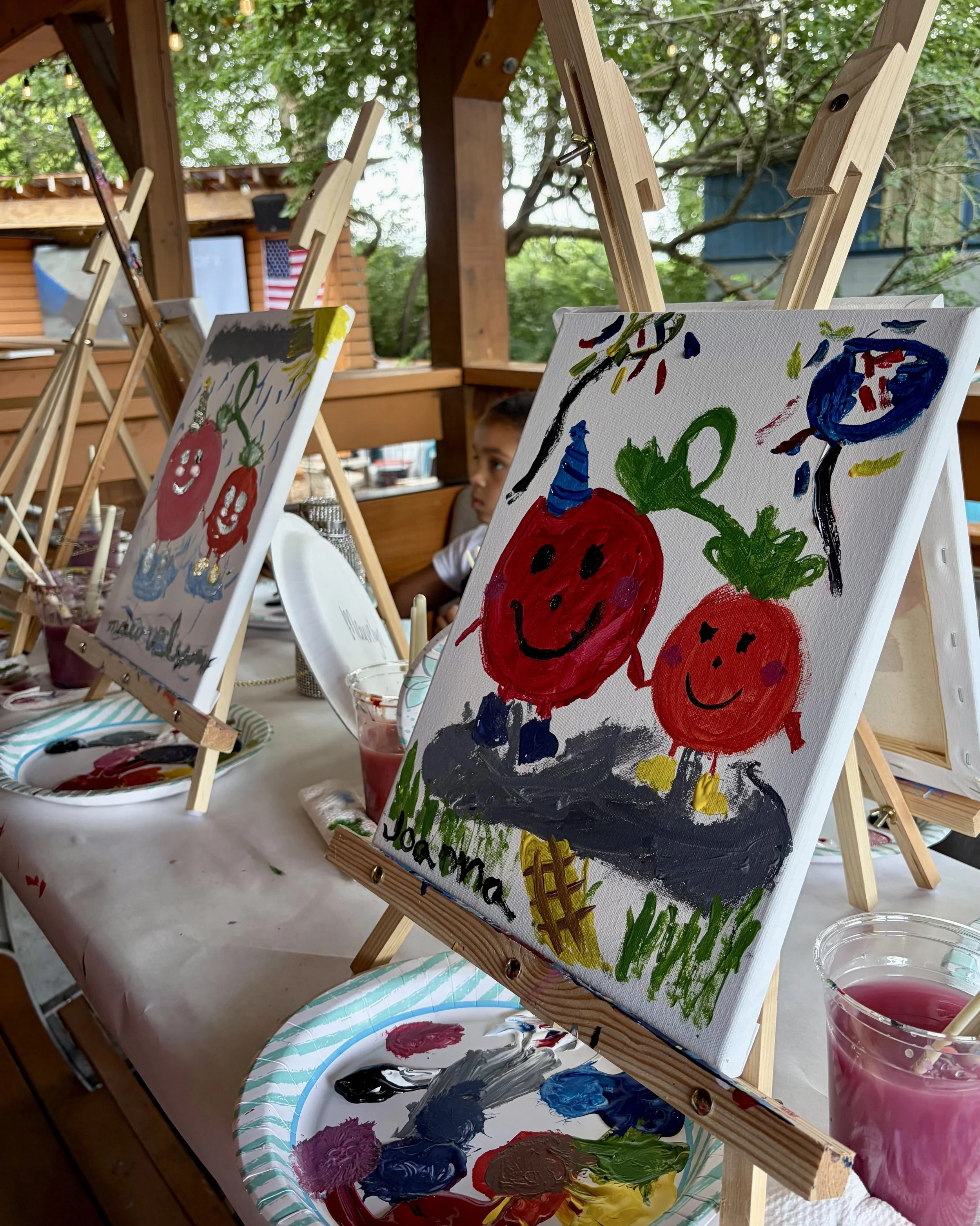 Close up of finished kids' tomato paintings in a line on a patio table