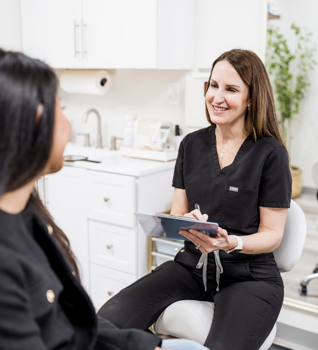 A female healthcare professional smiling and talking to a patient in a medical office.