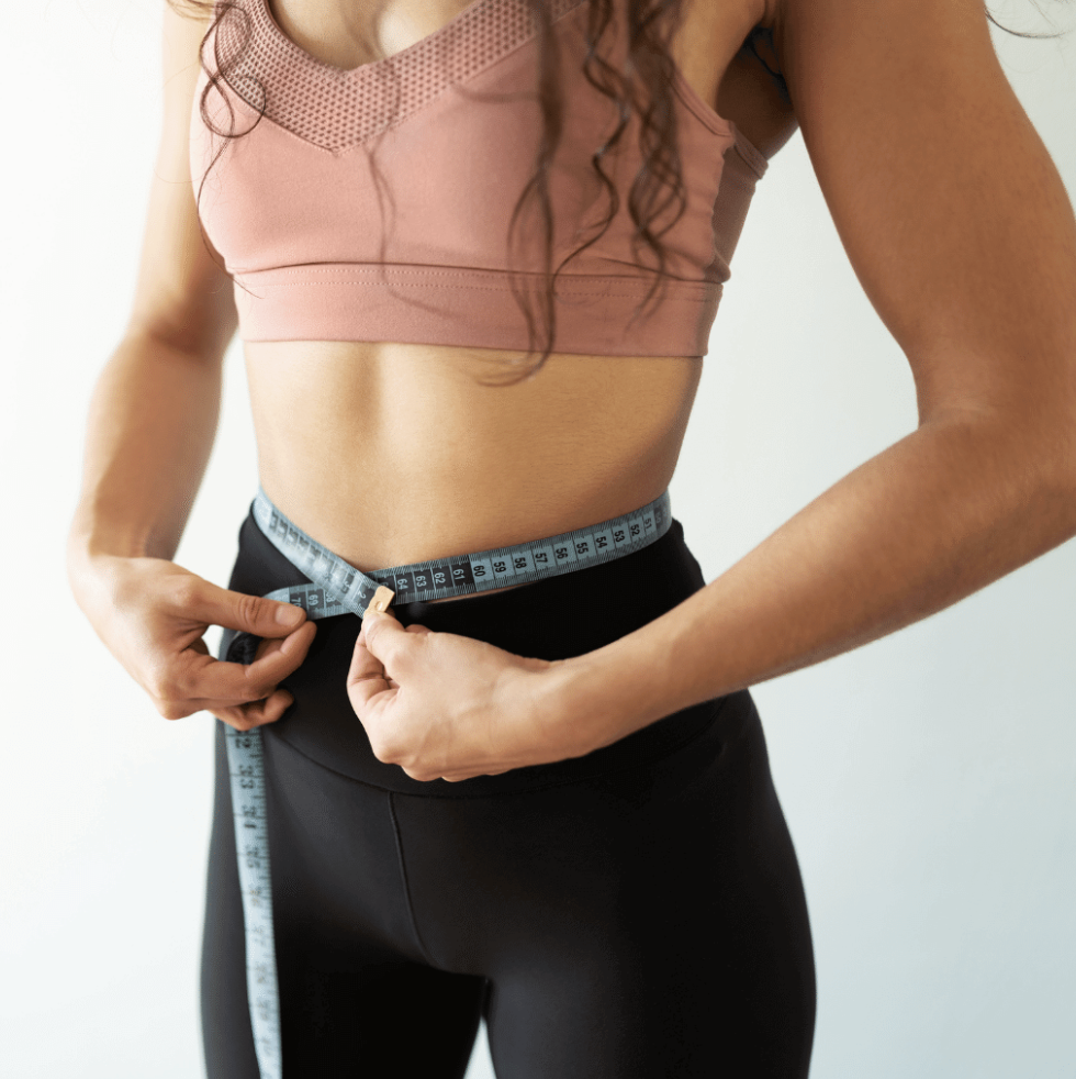 Person measuring their waist with a tape measure.