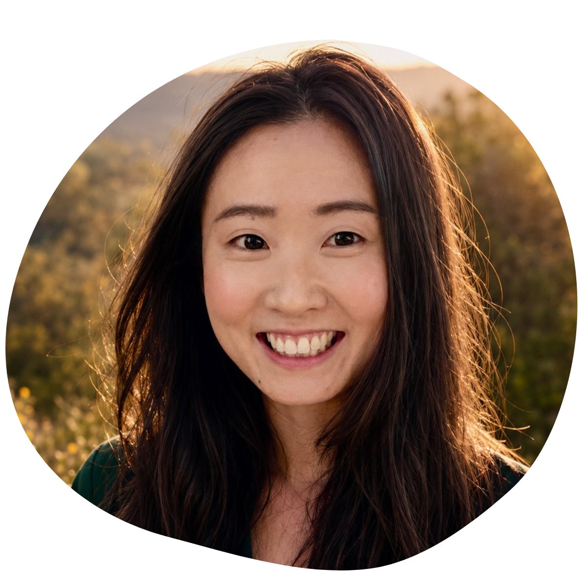 Professional headshot of a smiling woman with long dark hair, wearing a yellow top, looking directly at the camera
